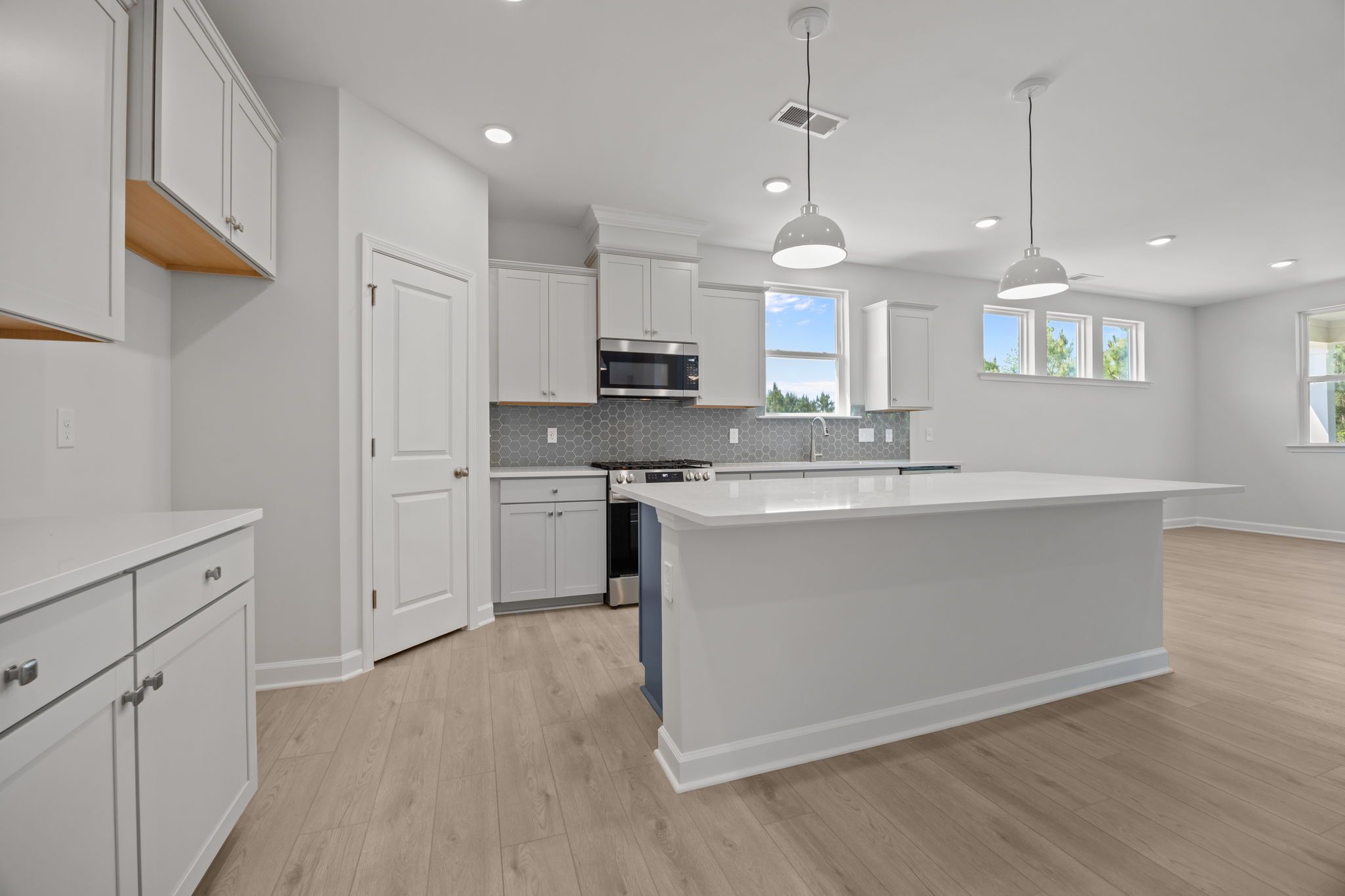 Modern kitchen in The Ashport B featuring white cabinetry, a large center island, and a stylish hexagonal tile backsplash.