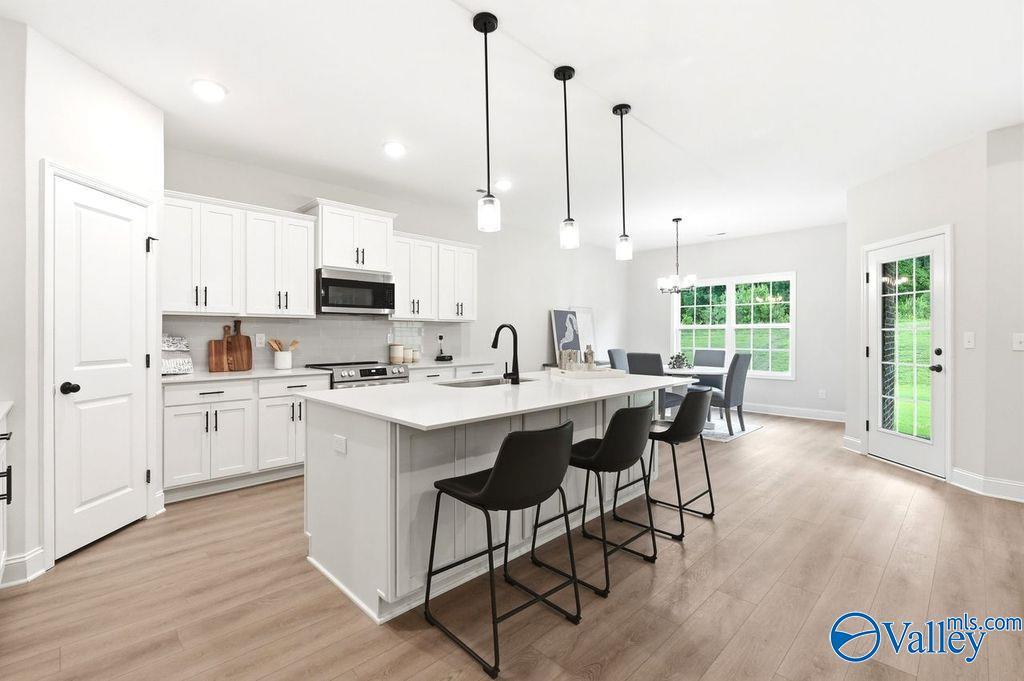 Modern kitchen with large island, pendant lighting, and white cabinets in The Rockford B floor plan at Cain Park, Hartselle.