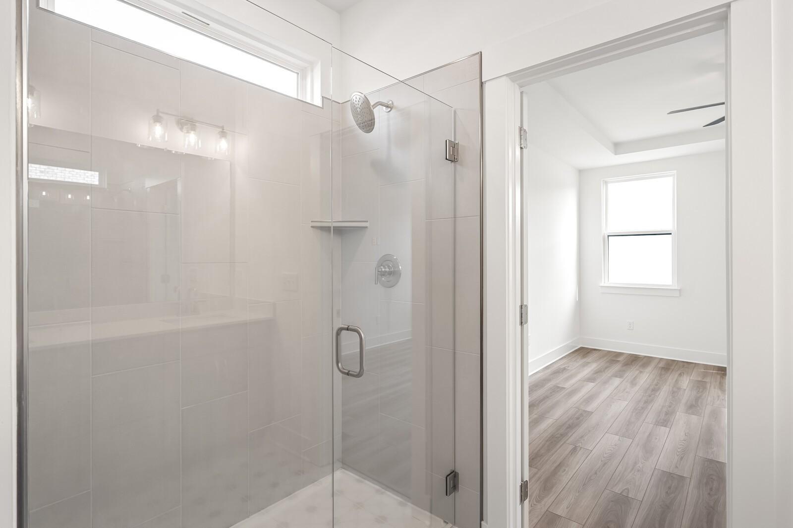 Modern frameless glass shower with rainfall head and subway tiles in master bath, adjacent to bedroom in Davidson Homes The Ash C, Mt. Juliet