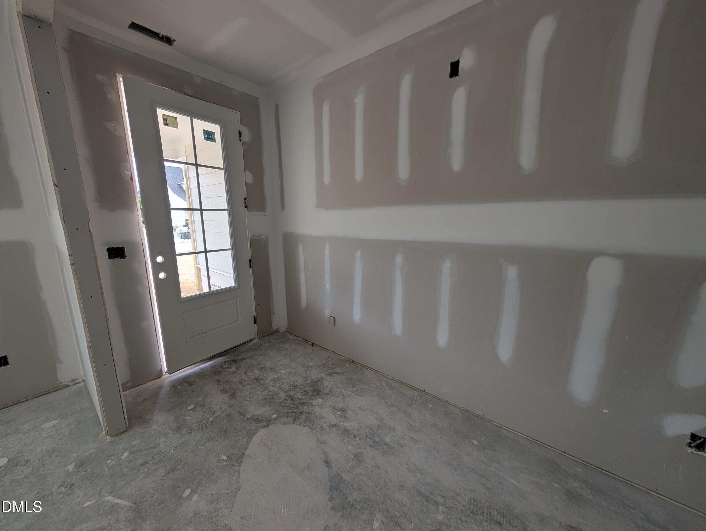 Unfinished foyer entry with glass-panel front door and drywall walls under construction in The Aspen C floor plan, Wendell Ridge, NC
