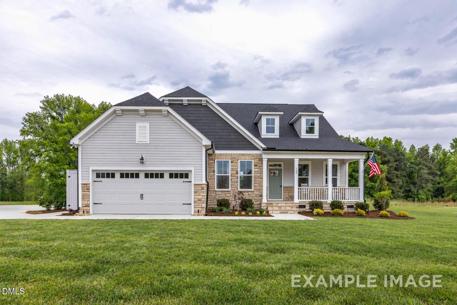 Front exterior of Davidson Homes' The Magnolia II B with covered porch, 2-car garage, and American flag in Addison West, Holly Springs, NC