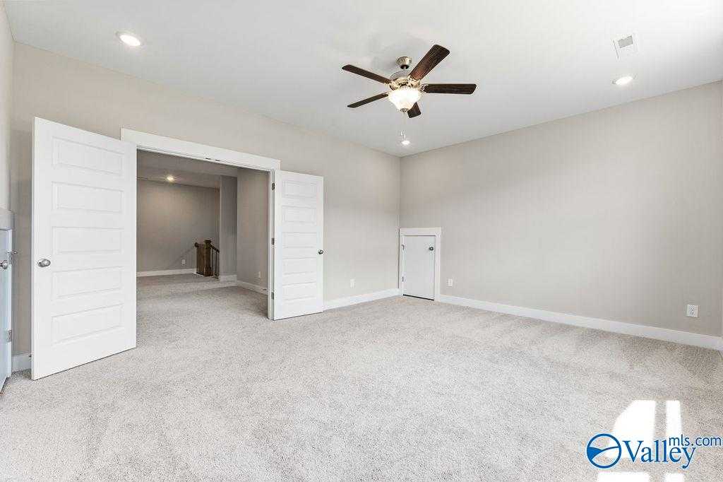 Open double doors to spacious bonus room with ceiling fan, beige walls, and carpet in Evermore Homes The Oxford, Owens Cross Roads