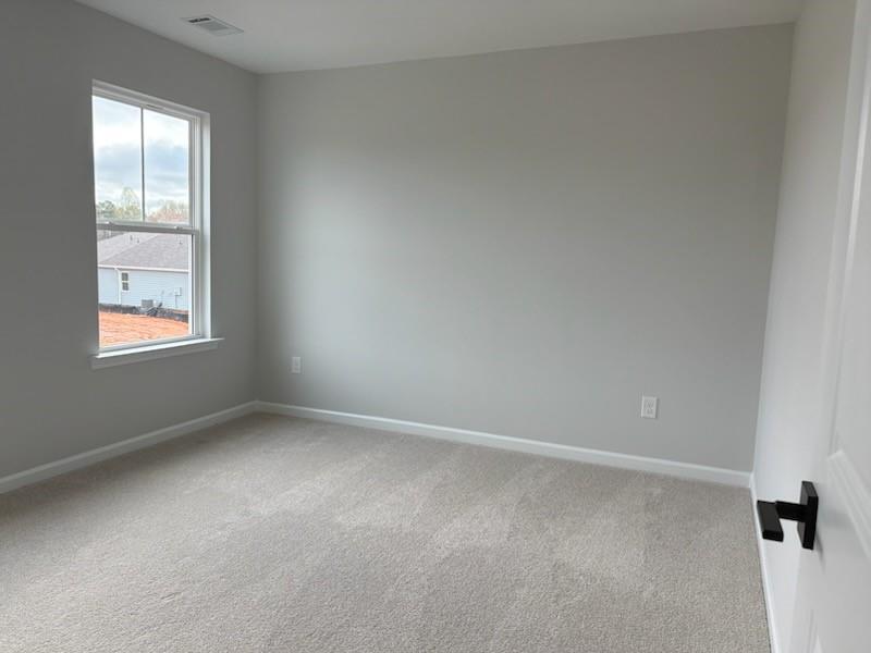 Empty bedroom with light gray walls, neutral carpet, and large window in Davidson Homes The Hickory B, Winder, Georgia