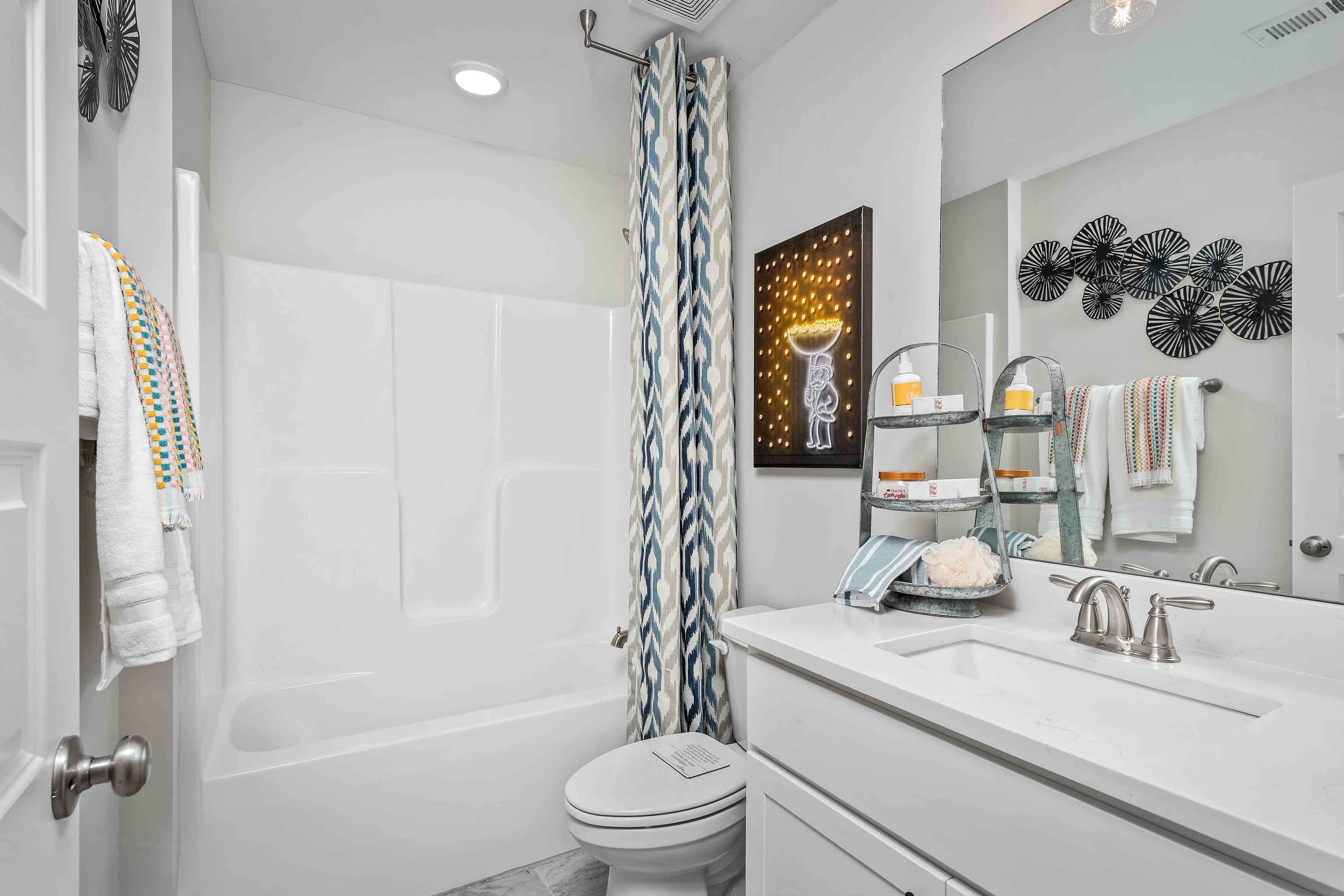 Modern bathroom at Cain Park in Hartselle, Alabama with white tub, vanity sink, blue shower curtain and yellow star artwork