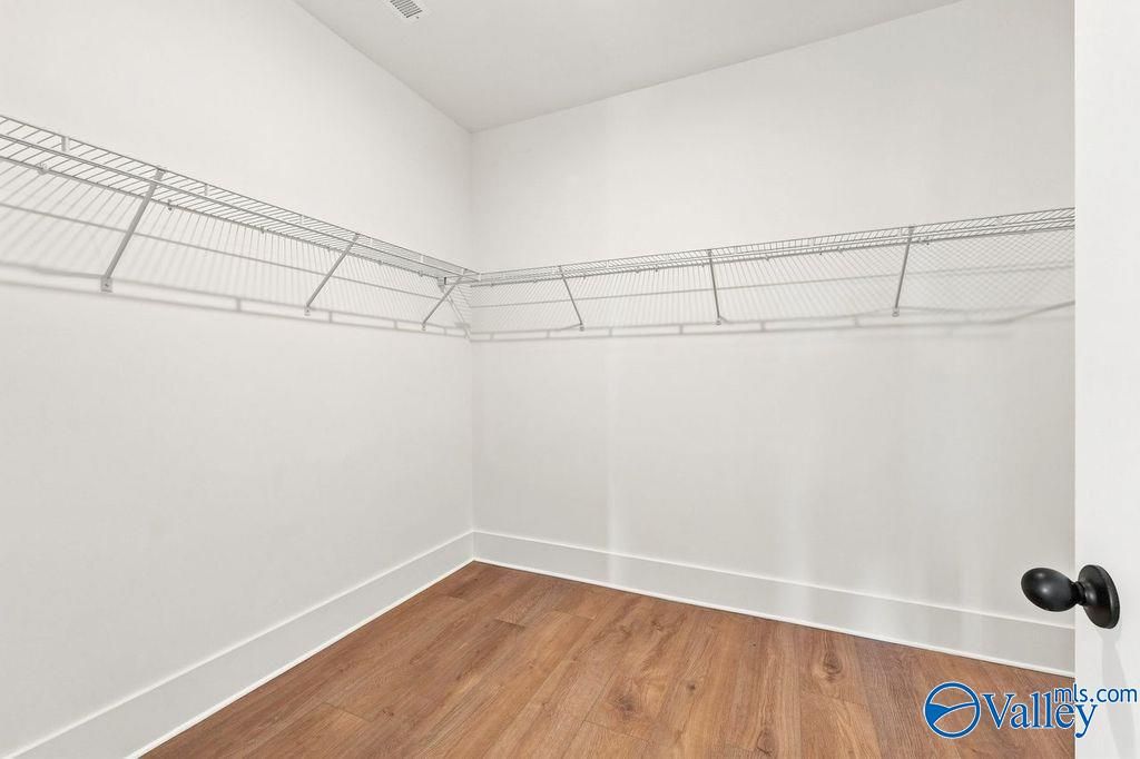 Walk-in closet with white wire shelving and wood-style flooring in The Rockford floor plan, Cain Park, Hartselle, Alabama.