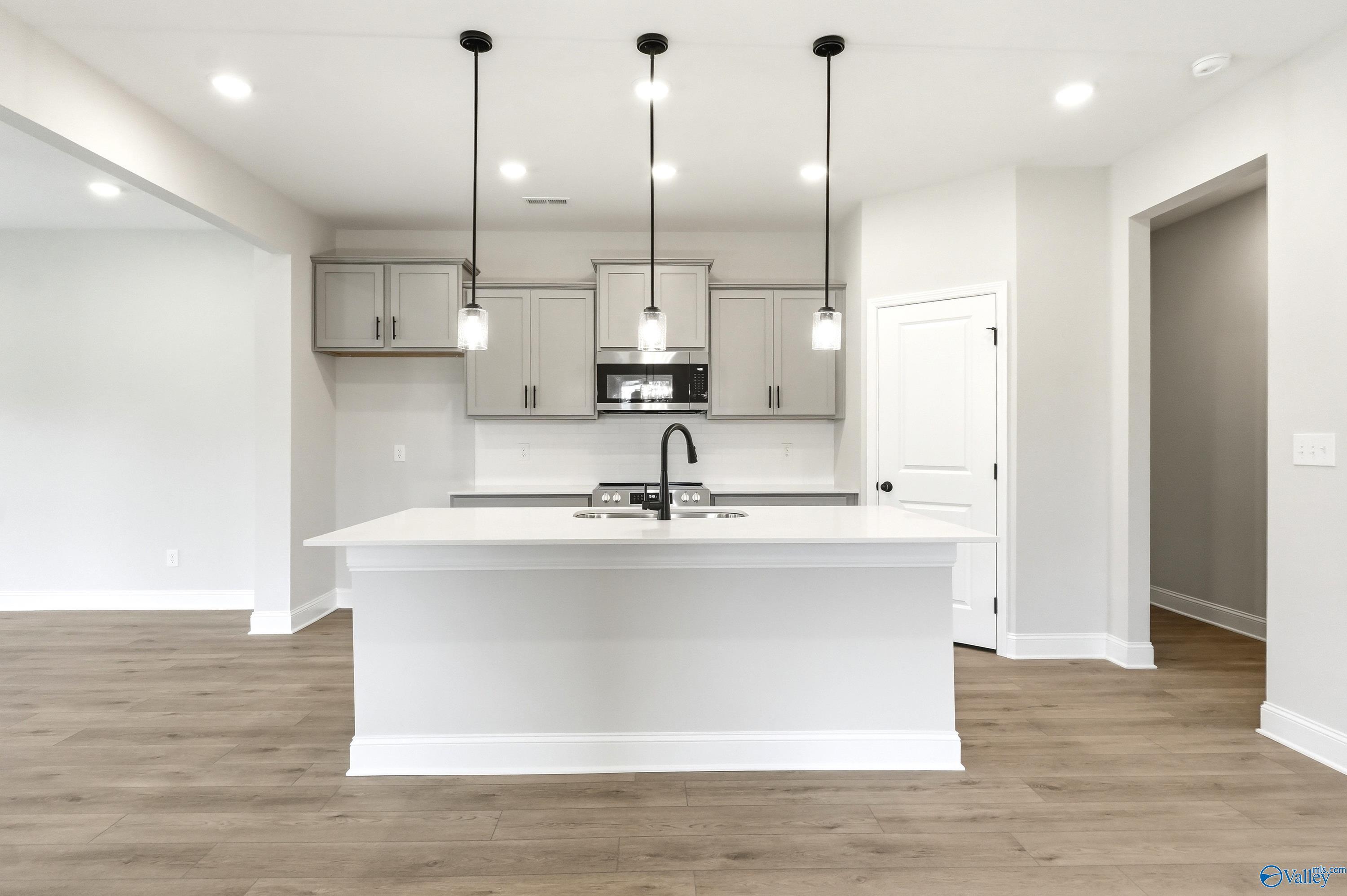 Modern kitchen with white island, gray cabinets, and pendant lighting in The Russell A floor plan, Spragins Cove, Huntsville.