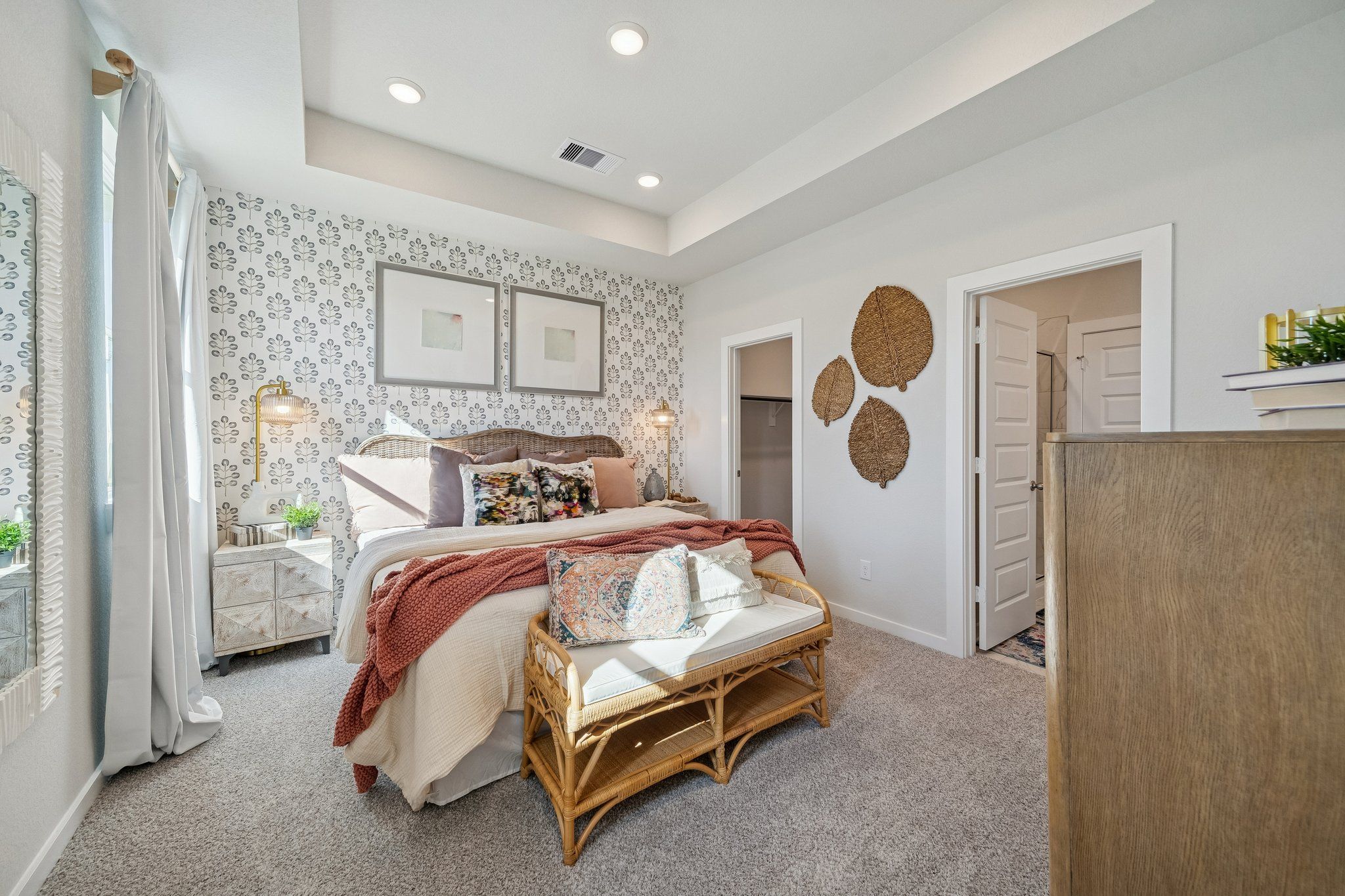 Spacious master bedroom at Spring Branch Crossing in Conroe TX with king bed, rattan wall decor, botanical wallpaper, and neutral tones