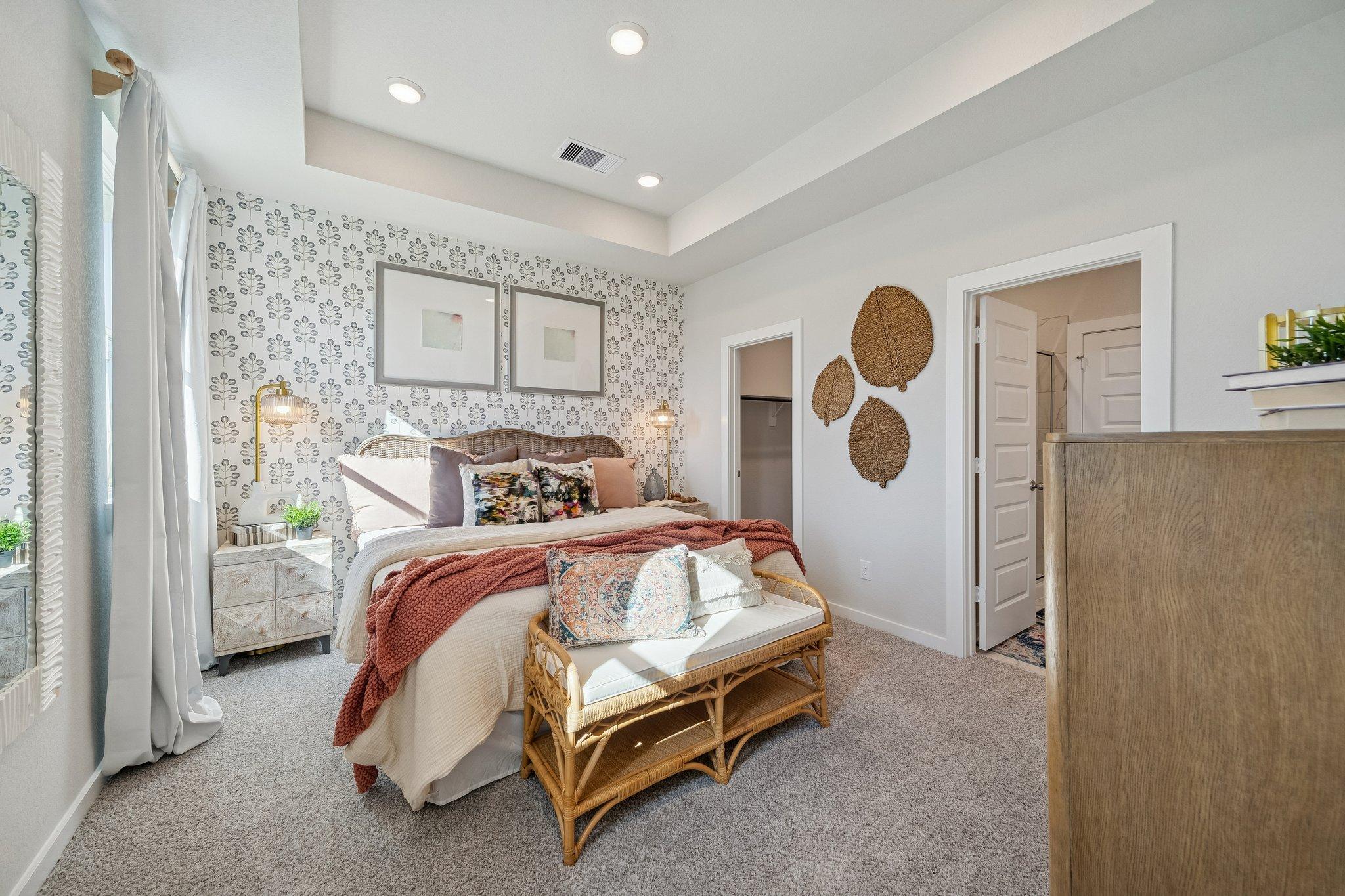 Spacious master bedroom at Spring Branch Crossing in Conroe TX with king bed, rattan wall decor, botanical wallpaper, and neutral tones