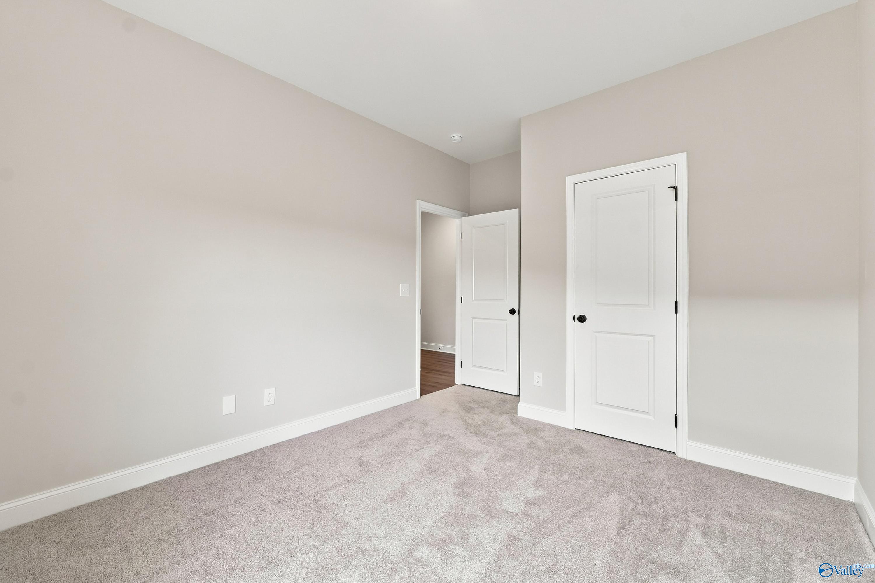 Bright, neutral-toned bedroom with plush carpet in The Asheville E floor plan by Davidson Homes in Forest Glen, Alabama.