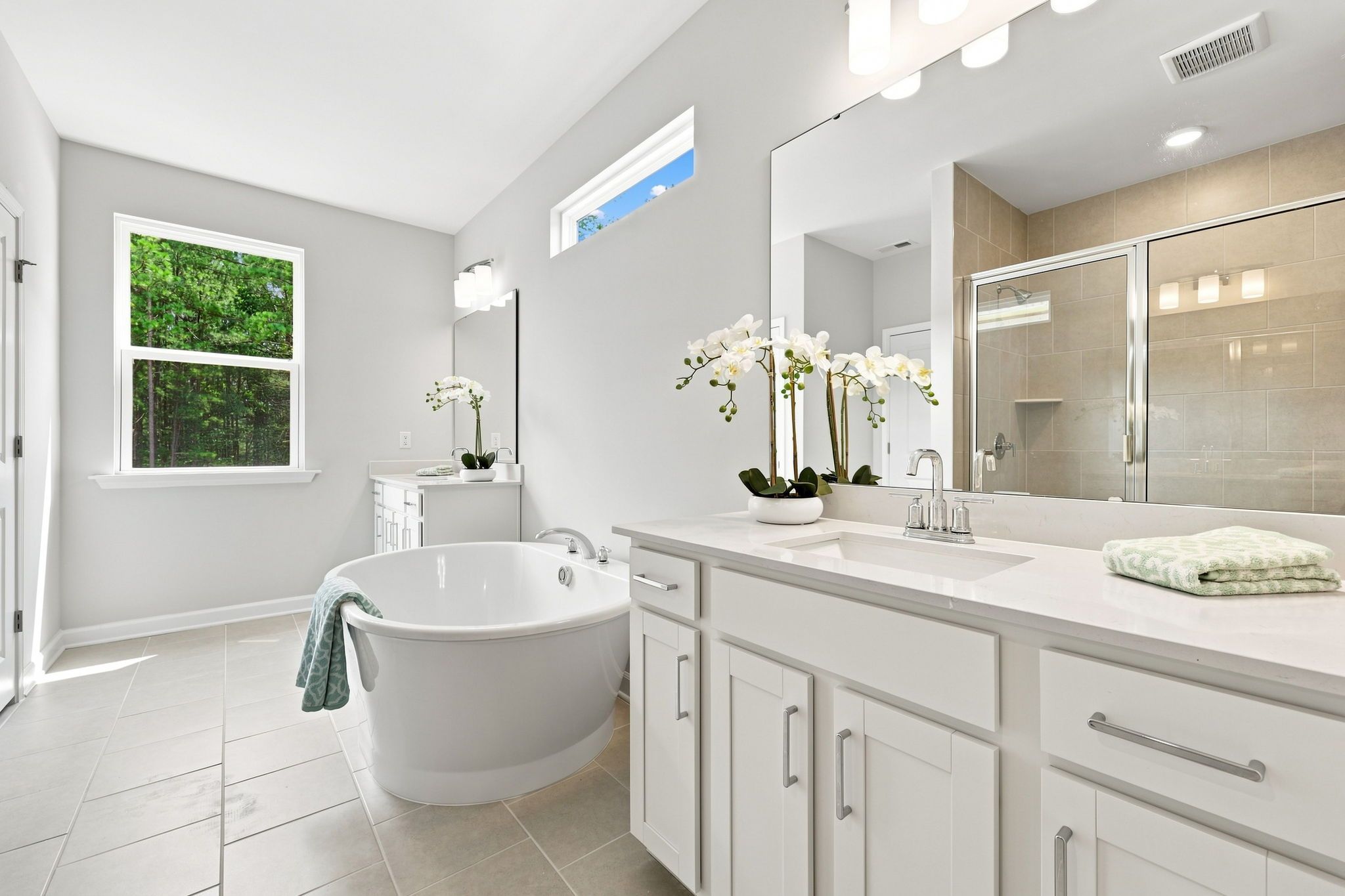 Spacious master bathroom in The Jordan A featuring a soaking tub, dual vanity, and walk-in tiled shower.