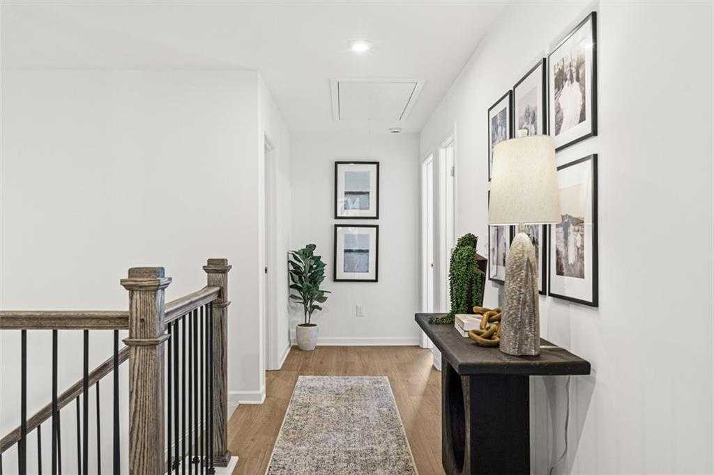Bright upstairs hallway with hardwood floors, runner rug, wooden balustrade, and modern console in The Hickory B home, Hoschton, GA