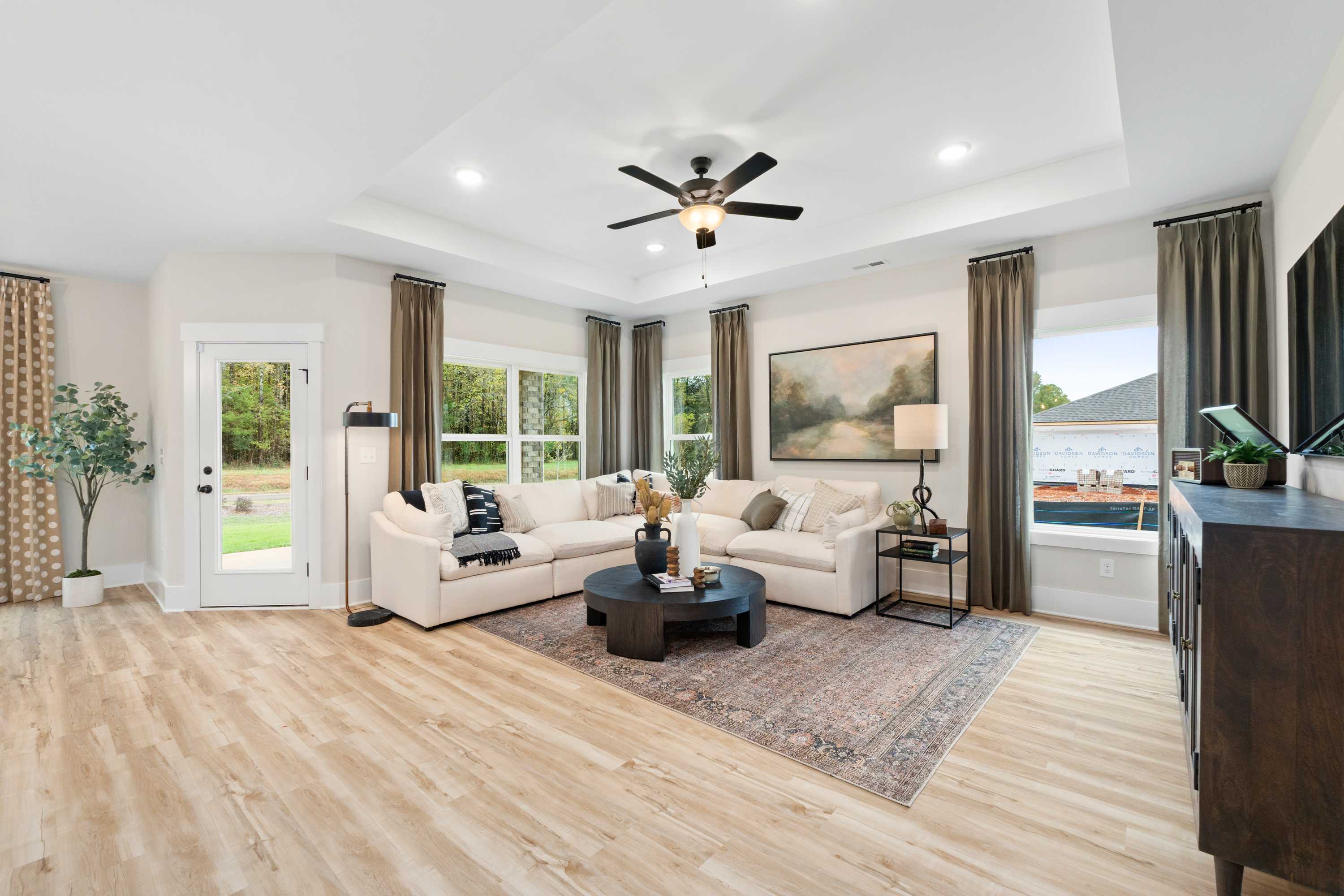 Spacious open-concept living room in Spragins Cove Huntsville AL with white sectional sofa, hardwood floors, ceiling fan and potted plants