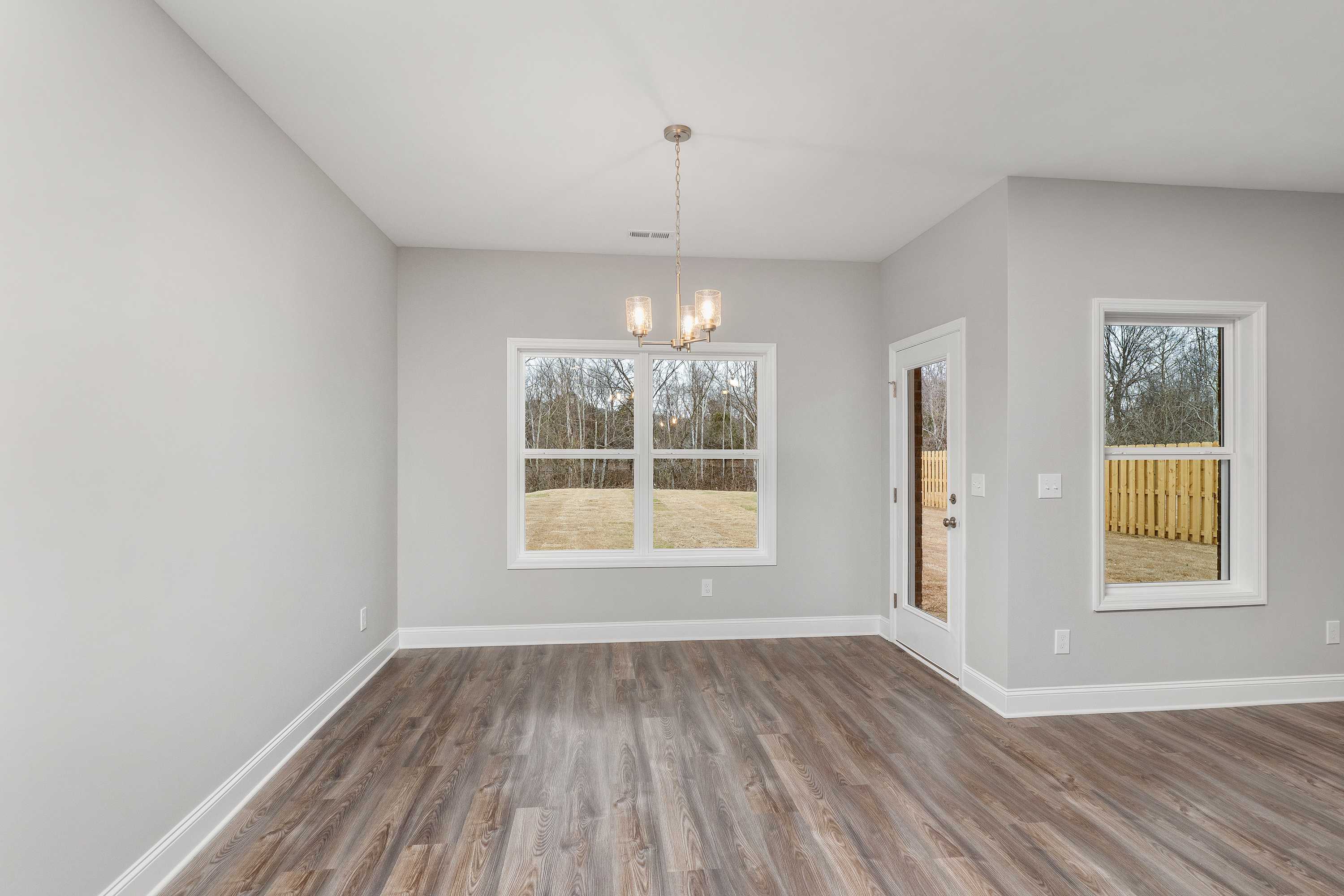 Spacious dining room in The Aiken with light gray walls, hardwood floors, large windows, and chandelier