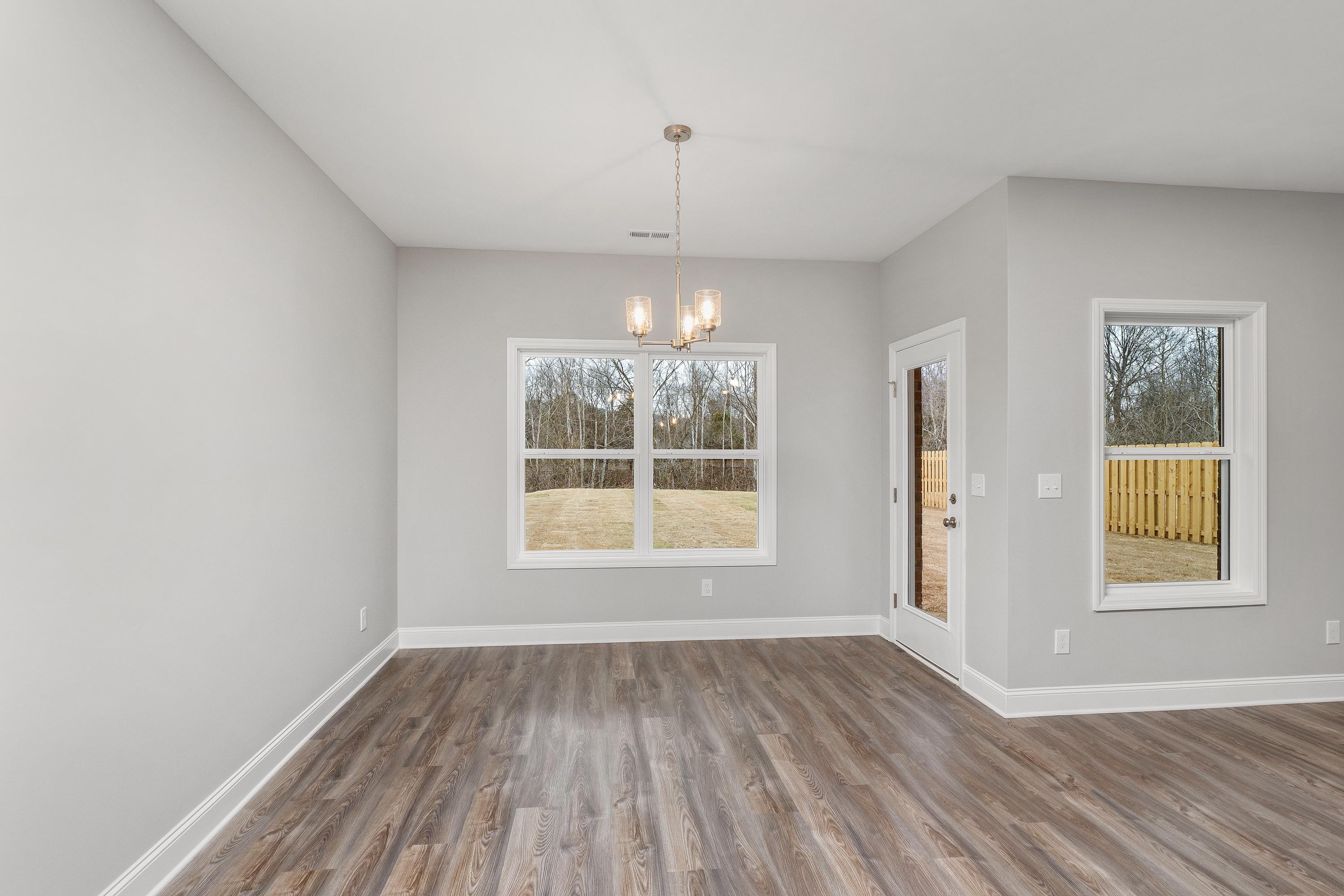 Spacious dining room in The Aiken with light gray walls, hardwood floors, large windows, and chandelier