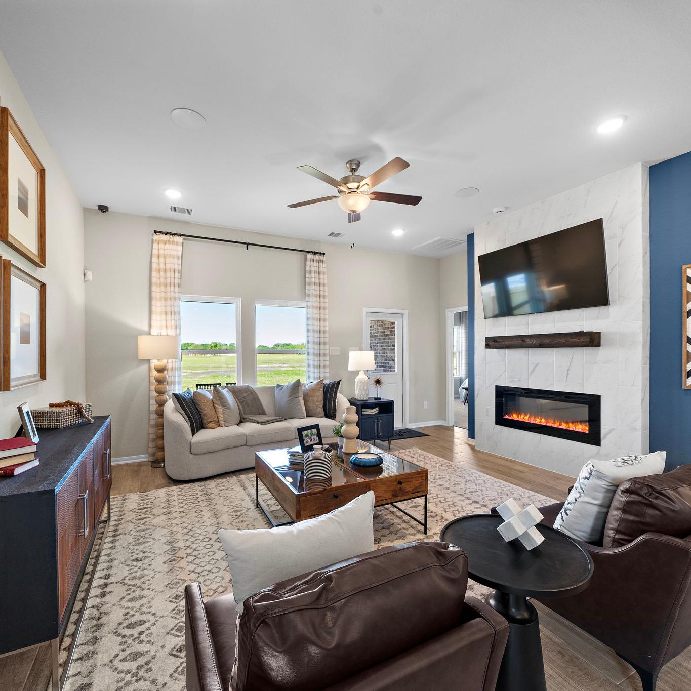 Open-concept living room in Emberly Beasley Texas with gray sectional sofa, gas fireplace, blue accent wall, hardwood floors