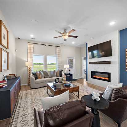Open-concept living room in Emberly Beasley Texas with gray sectional sofa, gas fireplace, blue accent wall, hardwood floors