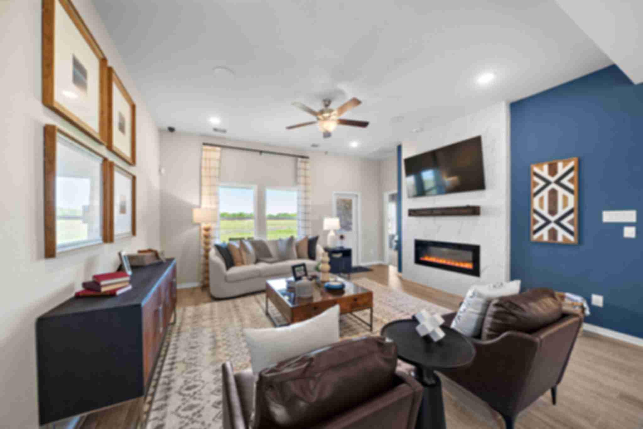 Open-concept living room in Emberly Beasley Texas with gray sectional sofa, gas fireplace, blue accent wall, hardwood floors