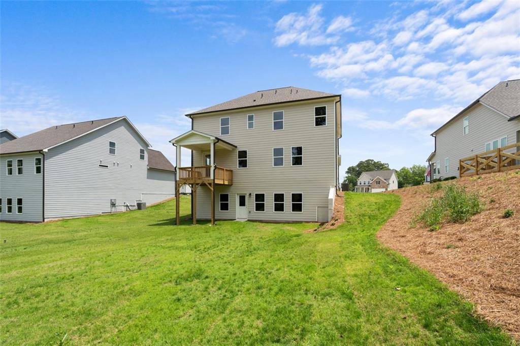 Rear view of three-story Davidson Homes The Willow D with deck overlooking green lawn in Wehunt Meadows, Hoschton, Georgia