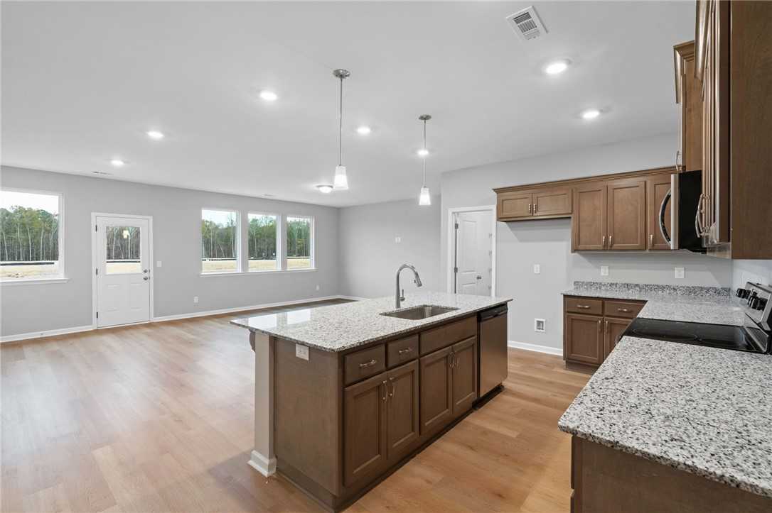Modern open-concept kitchen with granite island, stainless appliances, shaker cabinets in The Luna B, Opelika, AL