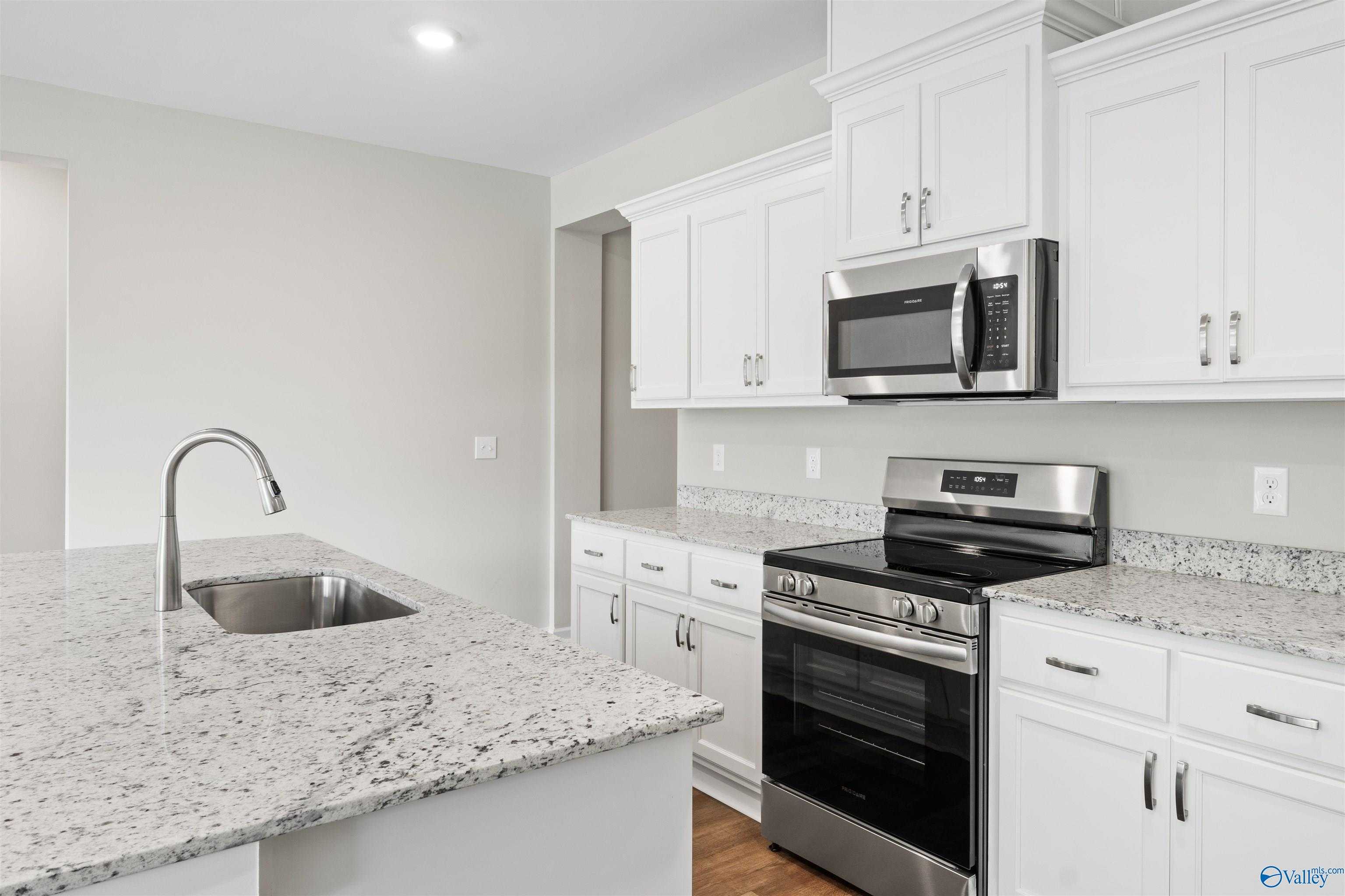 Modern kitchen with white shaker cabinets, granite island sink, stainless steel range in The Luna floor plan, Hazel Green, AL