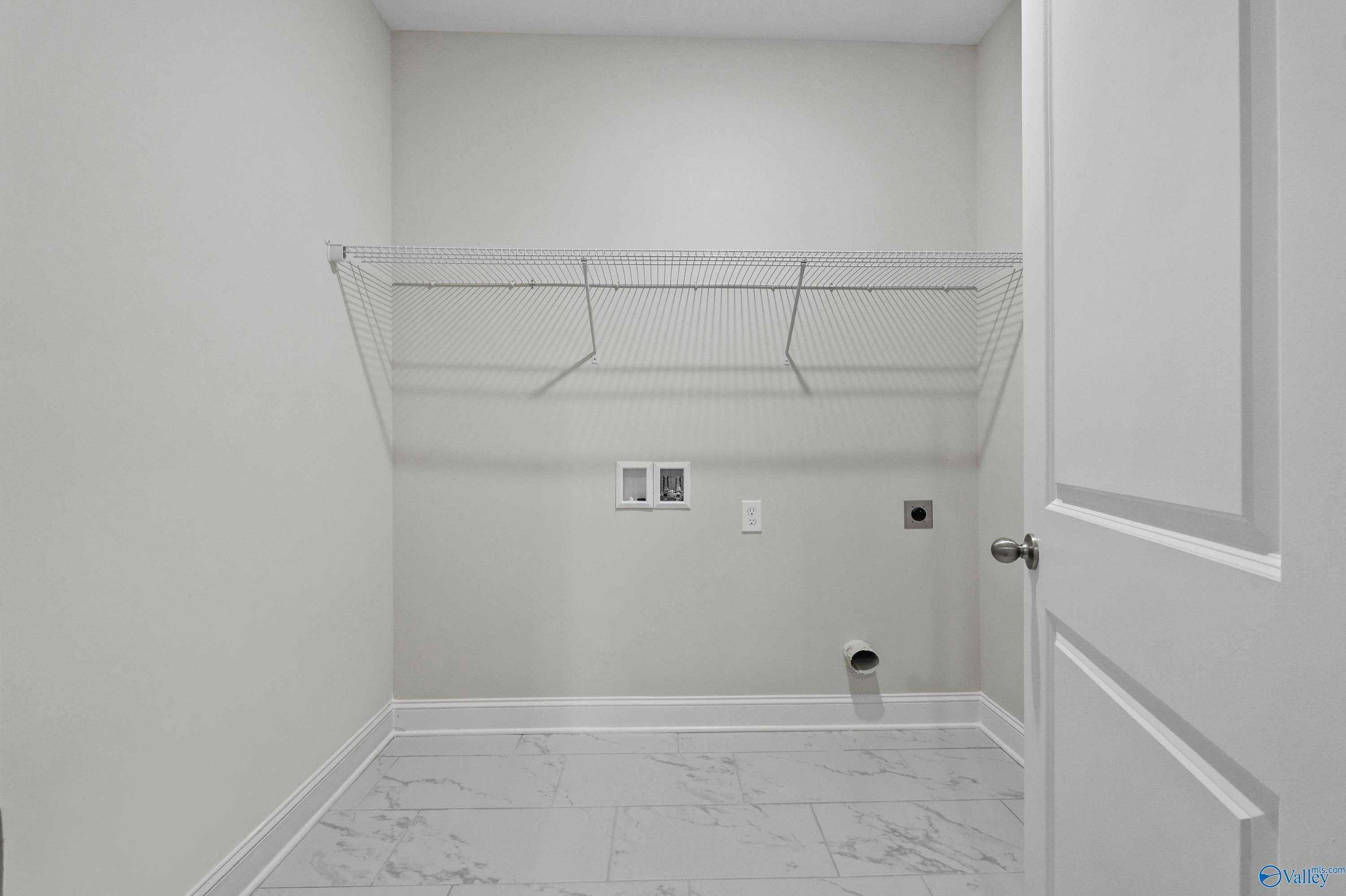 Functional laundry room with wire shelving, washer/dryer hookups, and tile flooring in Davidson Homes The Lanier, Harvest, Alabama