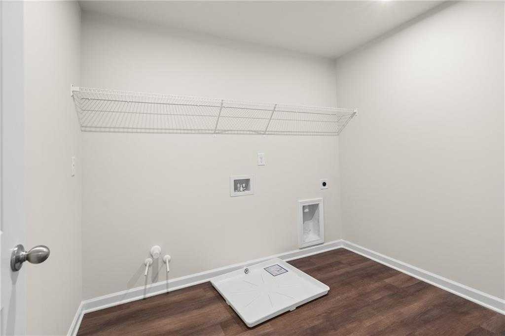 Modern laundry room with front-load washer, dryer, utility sink, wire shelving on hardwood floors in Davidson Homes The Marion B, Kennesaw, Georgia