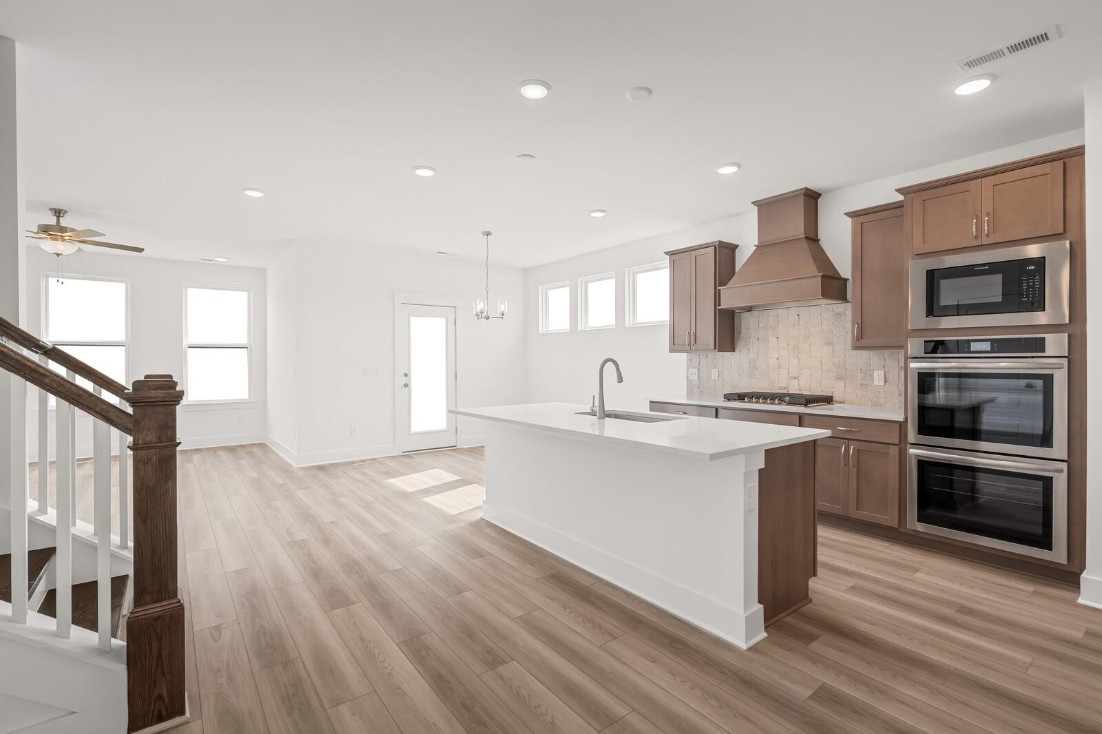Modern open-concept kitchen with white quartz island, stainless double ovens, subway tile backsplash in Davidson Homes The Ash C, Mt. Juliet
