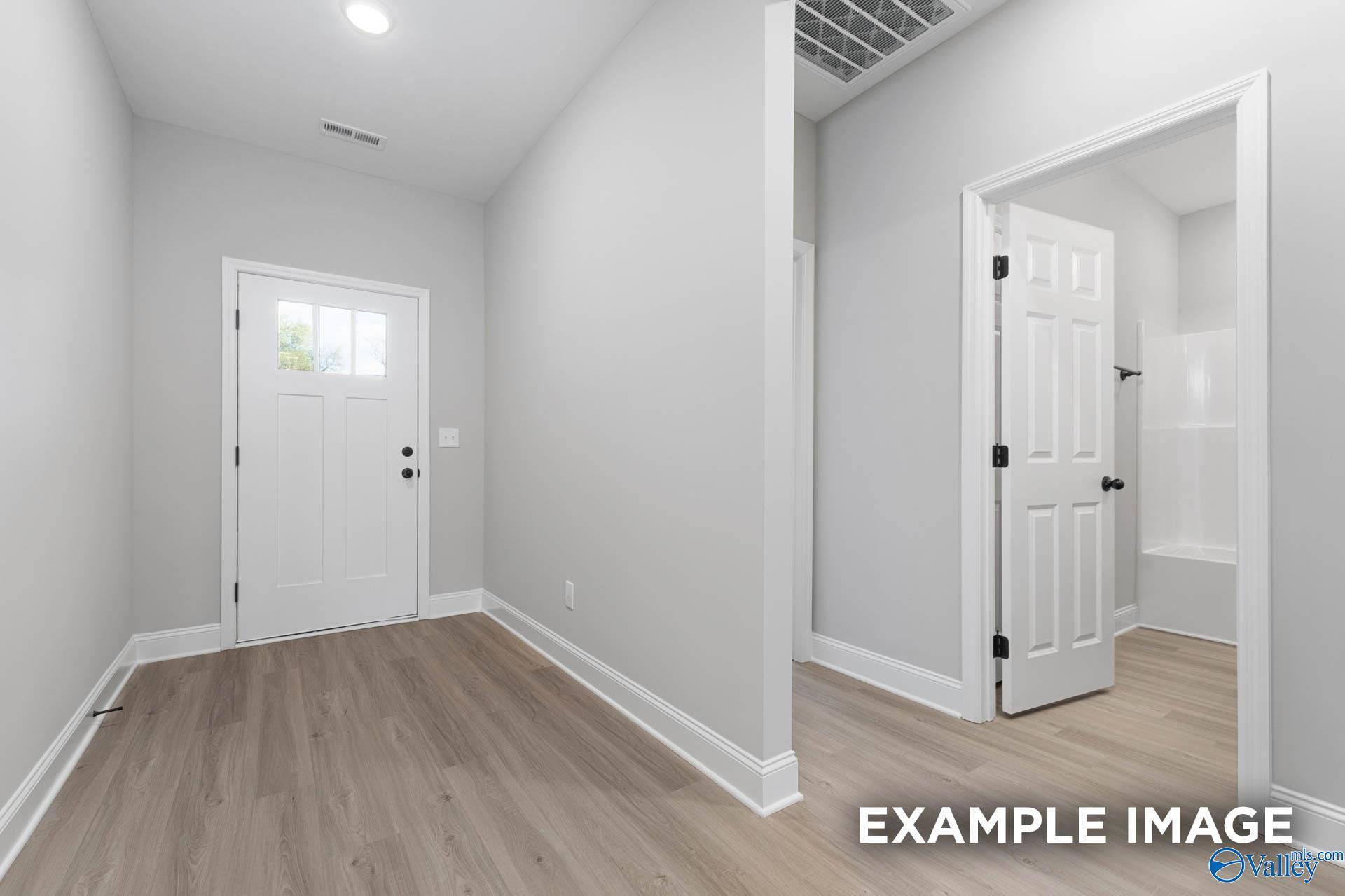 Bright foyer with luxury vinyl plank flooring and white front door in Davidson Homes The Daphne D, New Market, AL