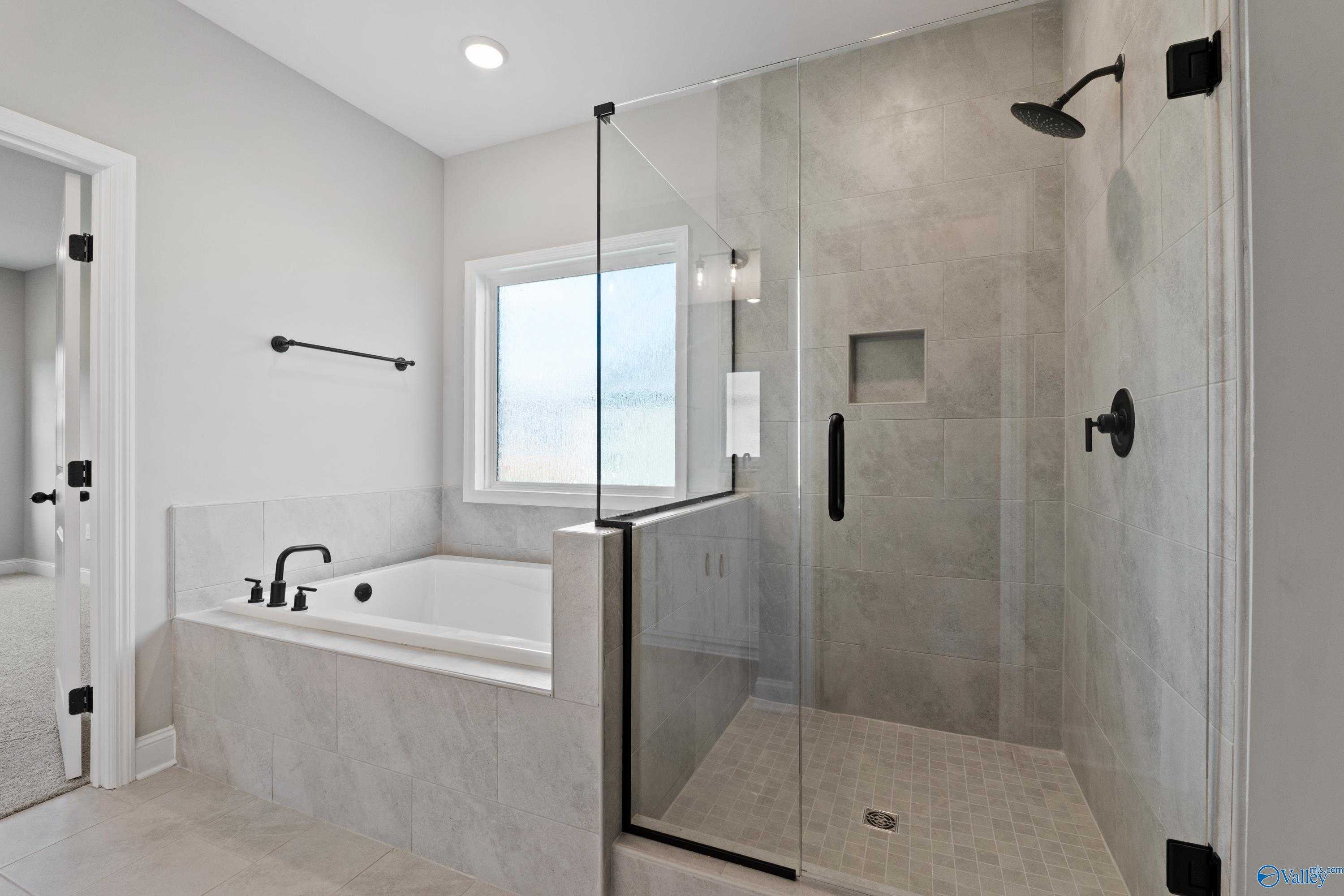 Modern master bath with frameless glass shower, soaking tub, and gray tile in Davidson Homes The Rockford with Bonus, Toney, AL