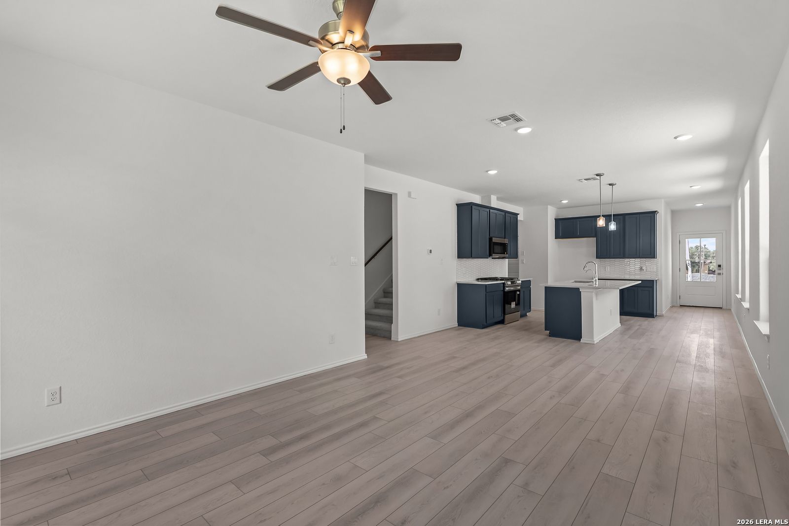 Open-concept living area with navy blue kitchen cabinets in The Gillian C floor plan at Meadows at Oak Creek, San Antonio.