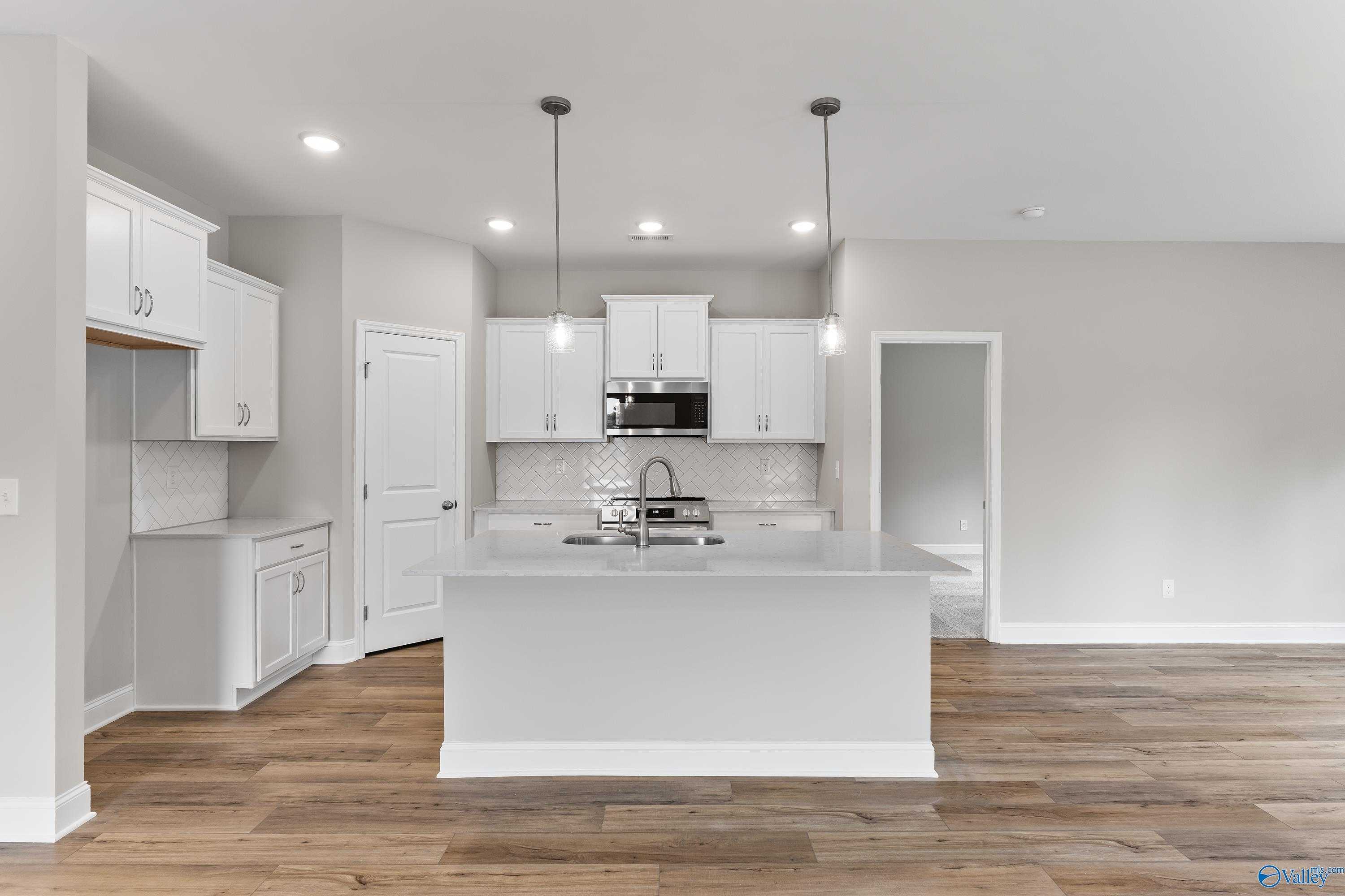 Modern white kitchen island with stainless steel range and sink, subway tile backsplash in Davidson Homes The Franklin, Huntsville AL