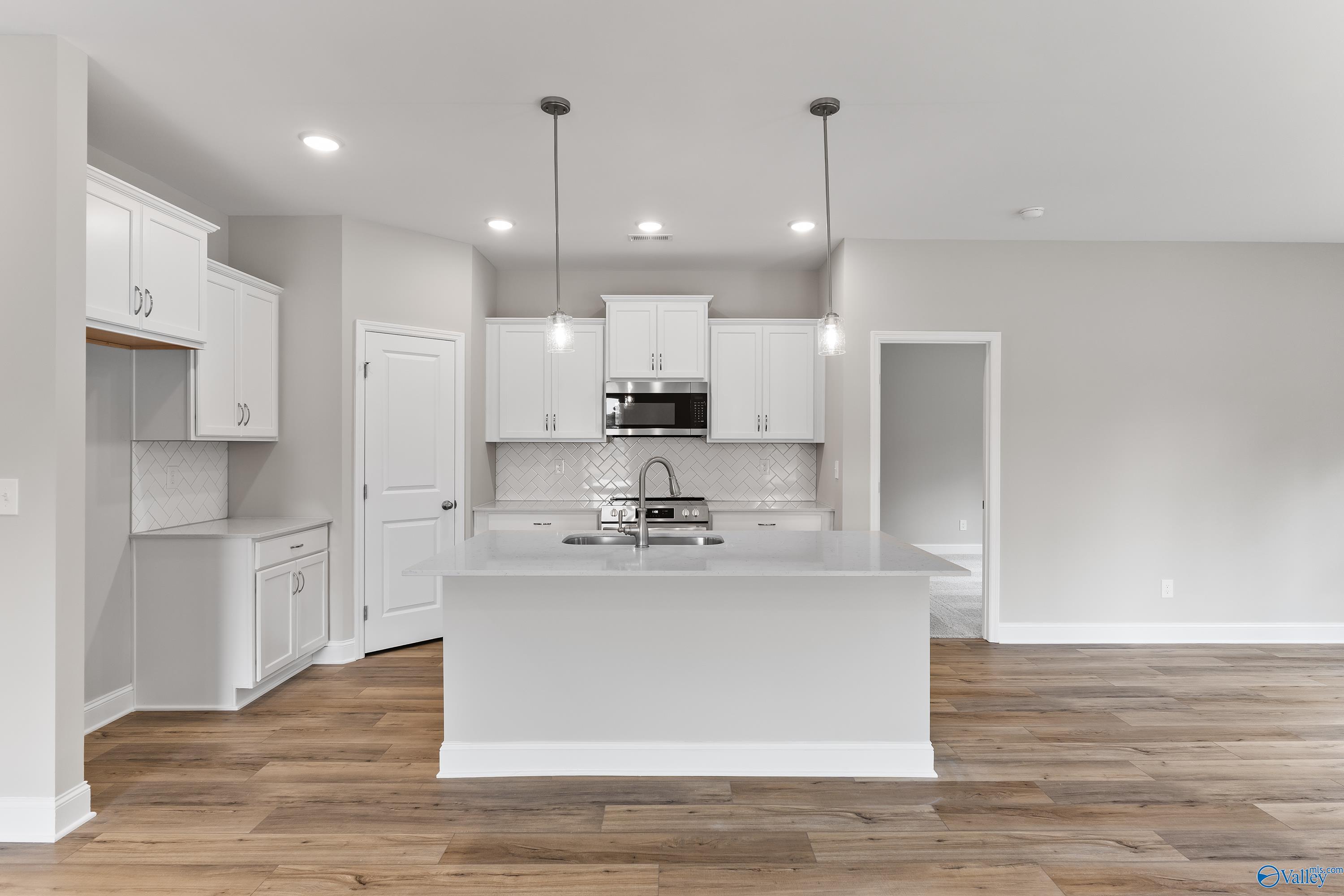 Modern white kitchen island with stainless steel range and sink, subway tile backsplash in Davidson Homes The Franklin, Huntsville AL