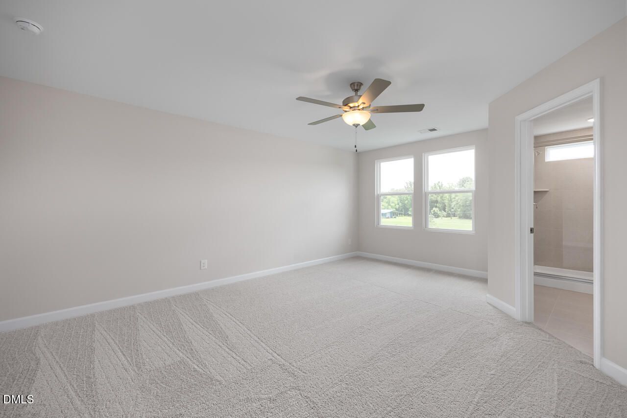 Spacious carpeted bedroom with ceiling fan in The Graham floor plan at Springvale, Fuquay-Varina, North Carolina.