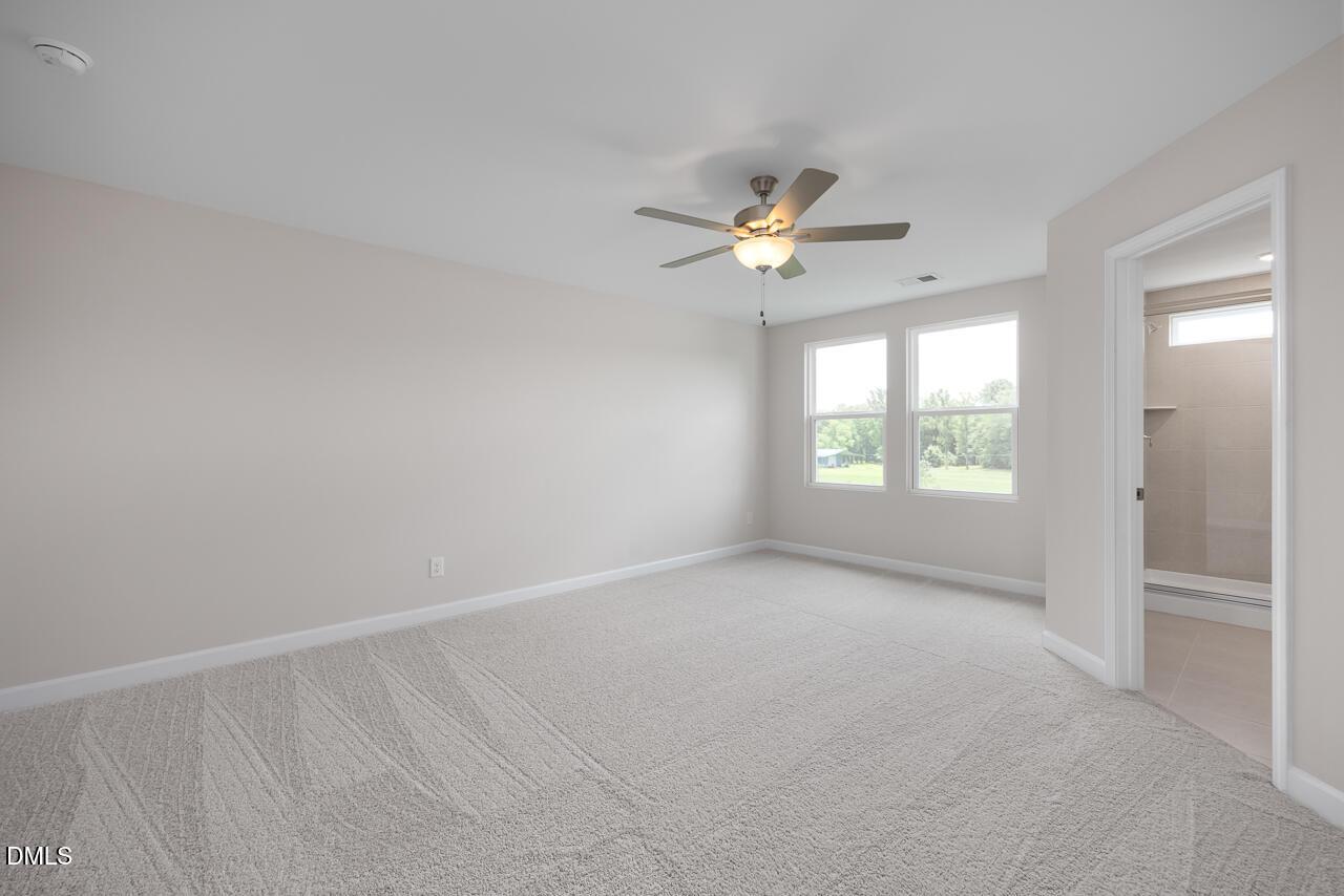 Spacious carpeted bedroom with ceiling fan in The Graham floor plan at Springvale, Fuquay-Varina, North Carolina.