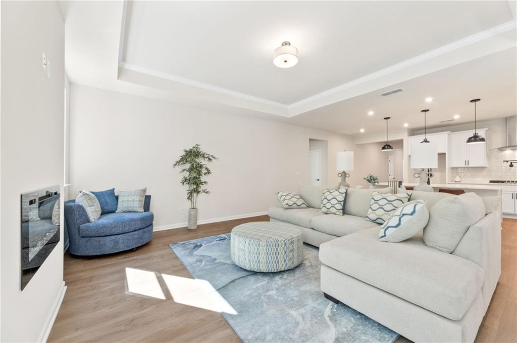 Cozy living room with gray sectional sofa, blue accent chair, ottoman, and electric fireplace in Davidson Homes The Daphne B, Loganville, GA