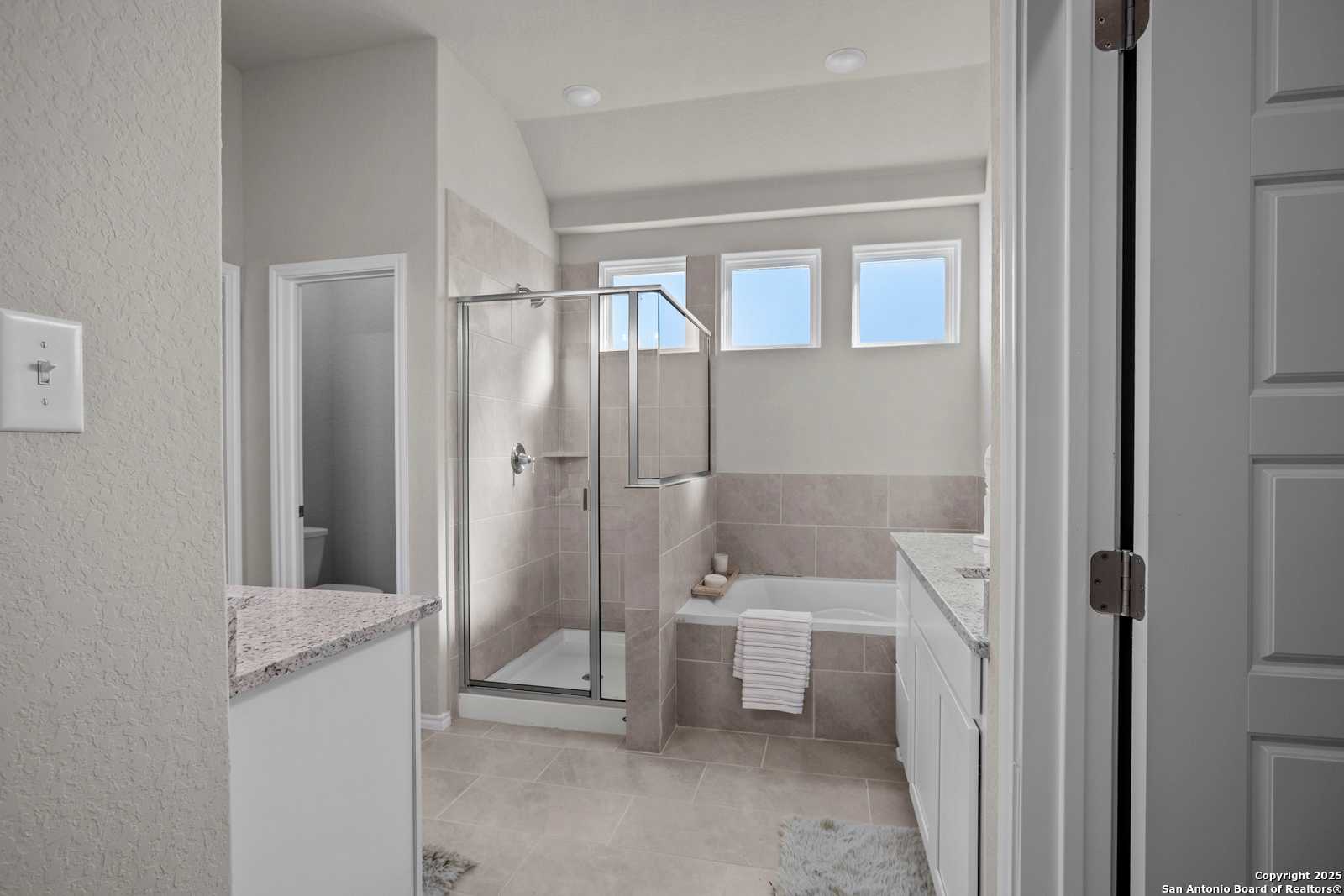 Modern master bathroom with frameless glass shower, soaking tub, and granite double vanity in Davidson Homes The Collin B, Seguin, Texas
