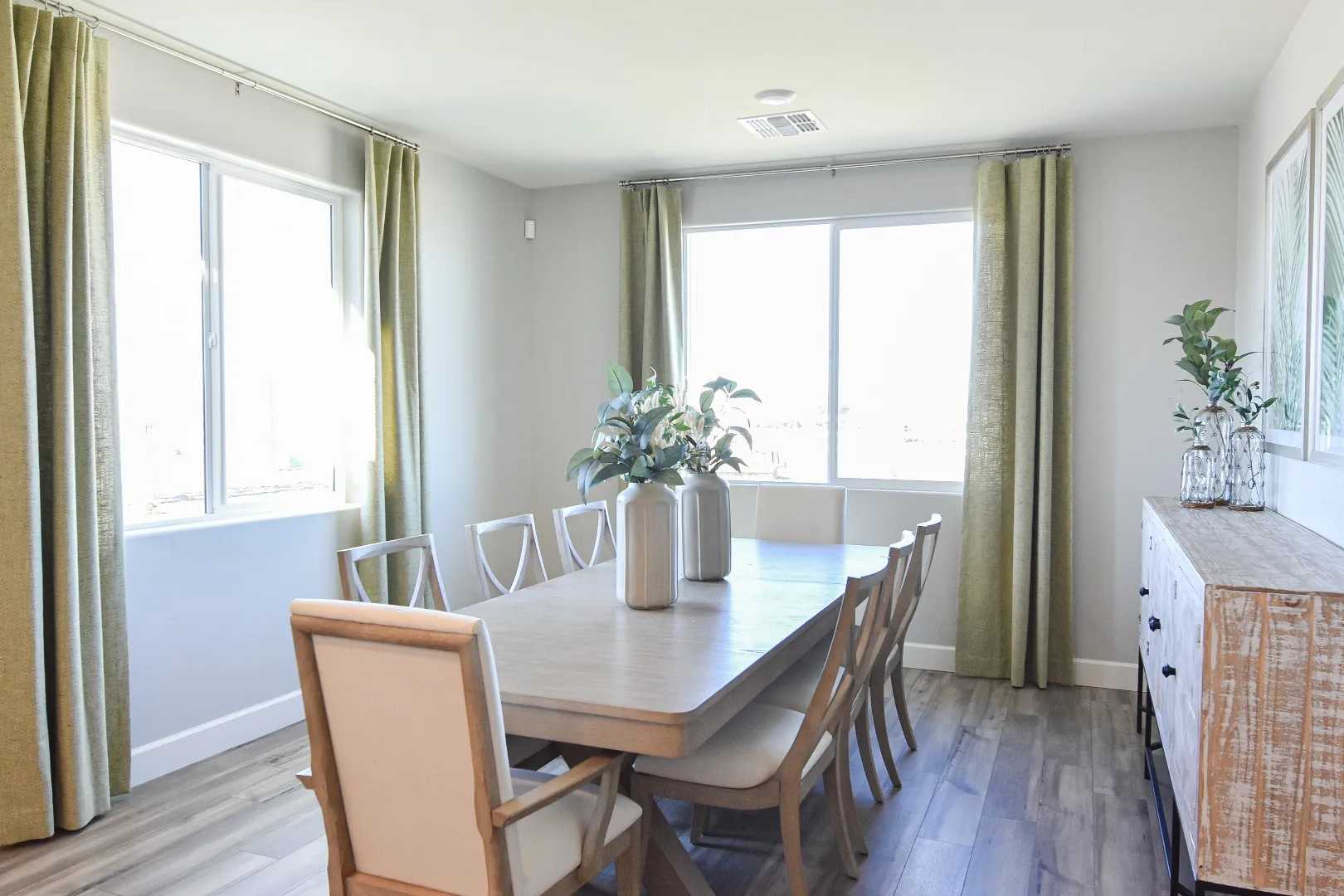 Spacious dining room at Morningstar in Prescott Valley AZ featuring long rectangular table, upholstered chairs, green curtains, and hardwood floors