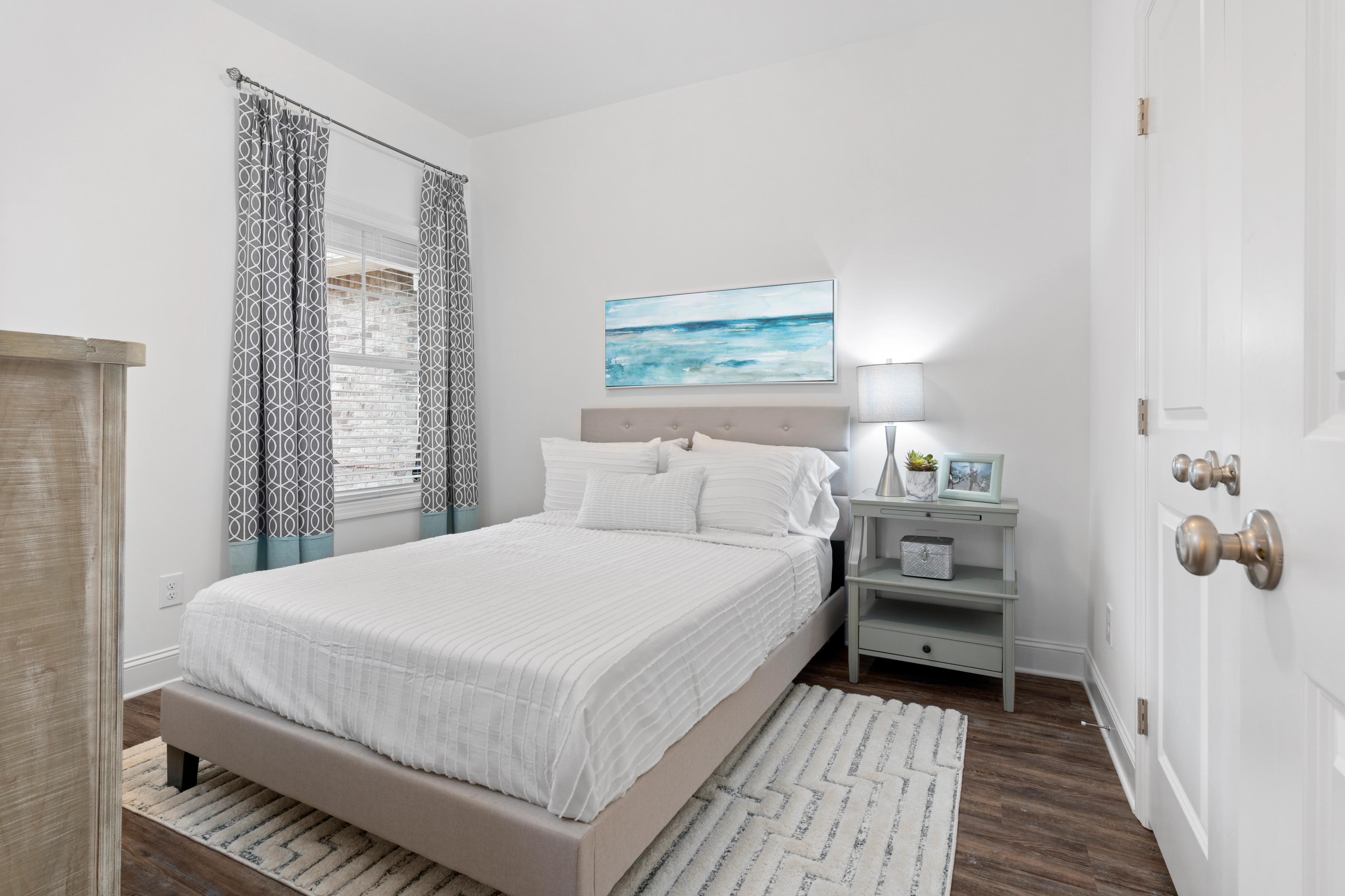 Modern secondary bedroom in The Cumberland B by Davidson Homes with queen bed, blue accents, and window light