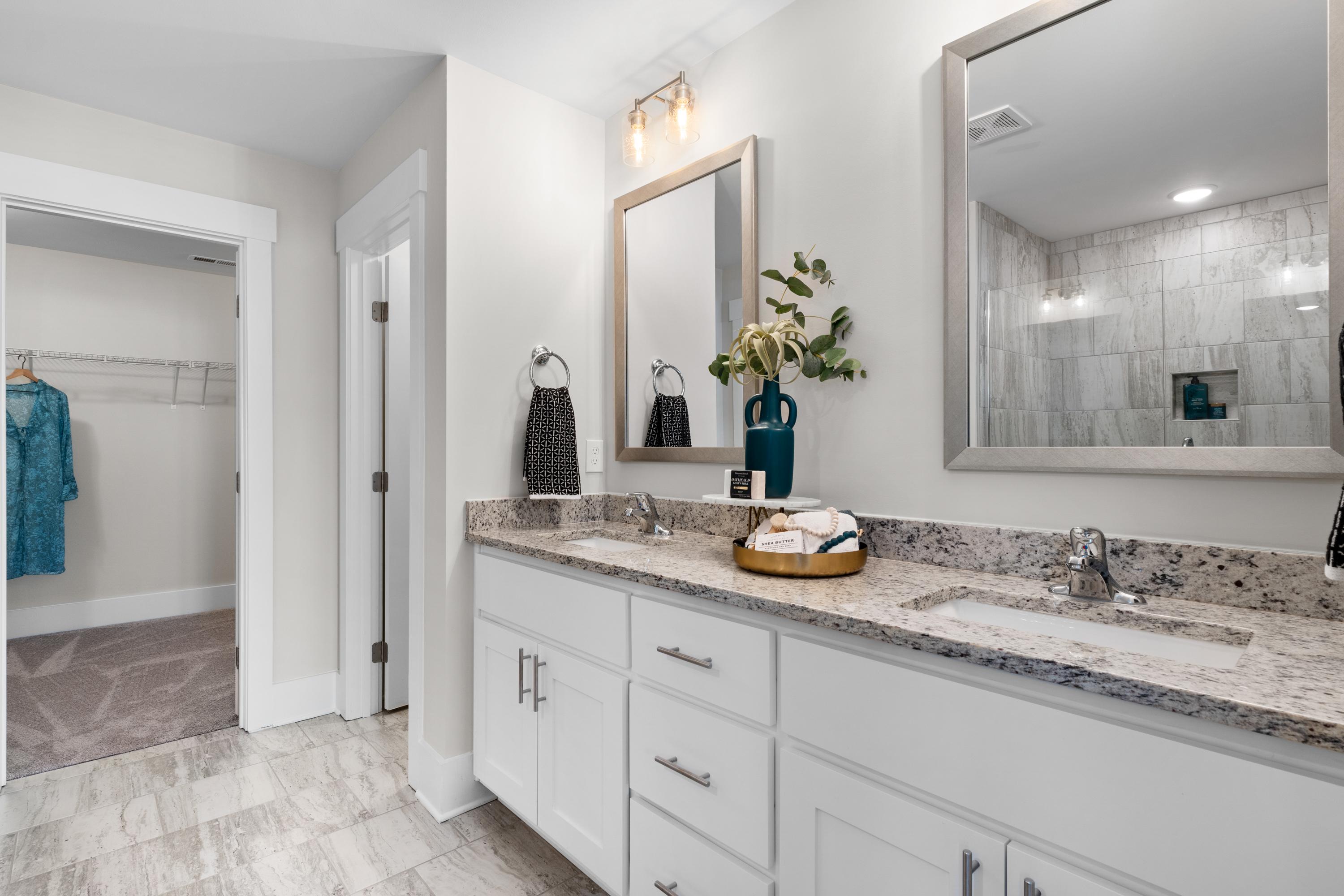 Spacious master bathroom in The Chelsea A with double vanity, granite counters, subway tile shower, and walk-in closet