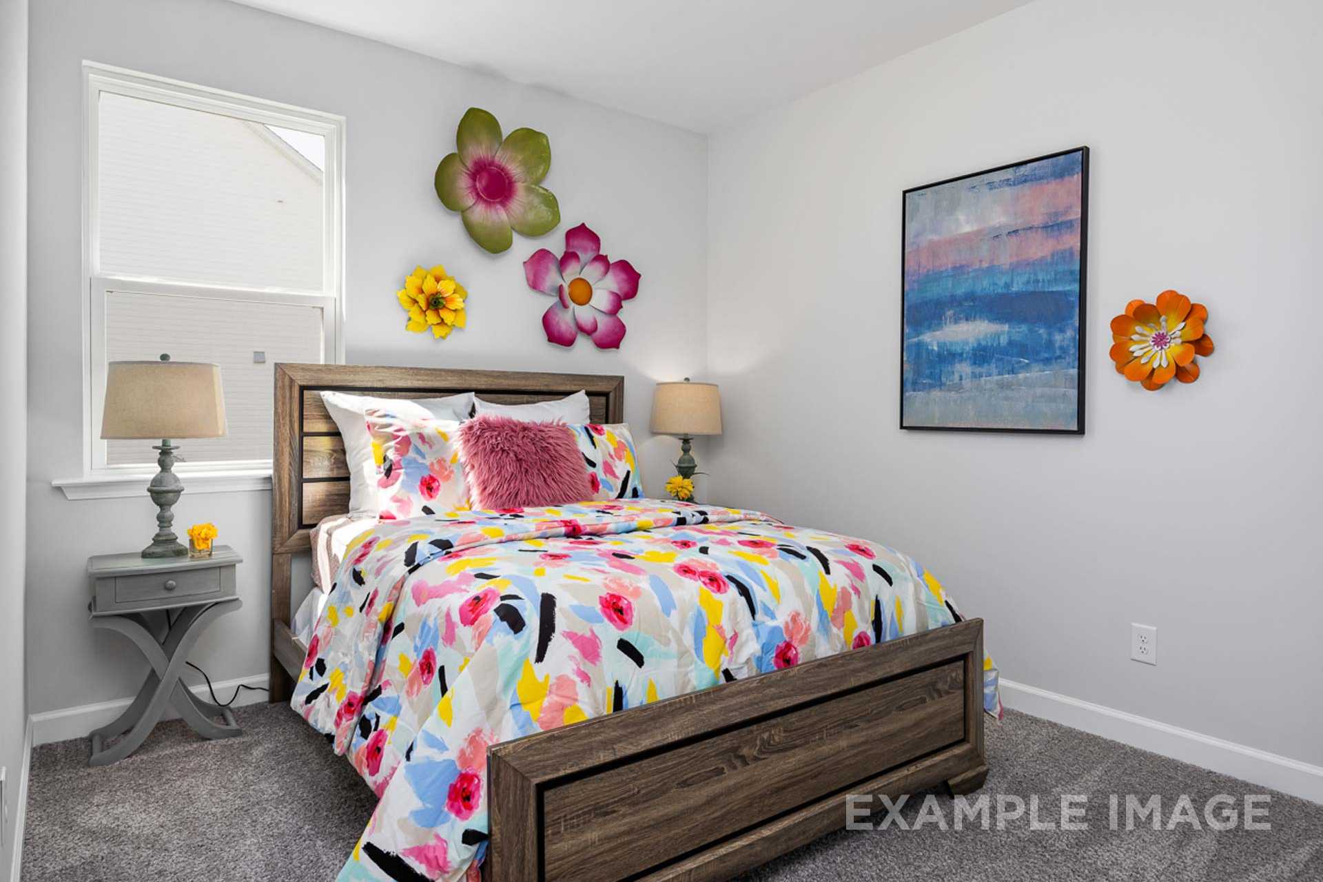Vibrant bedroom in The Carter B featuring wooden bed with colorful floral bedding, oversized wall flowers, abstract blue art, and lamps