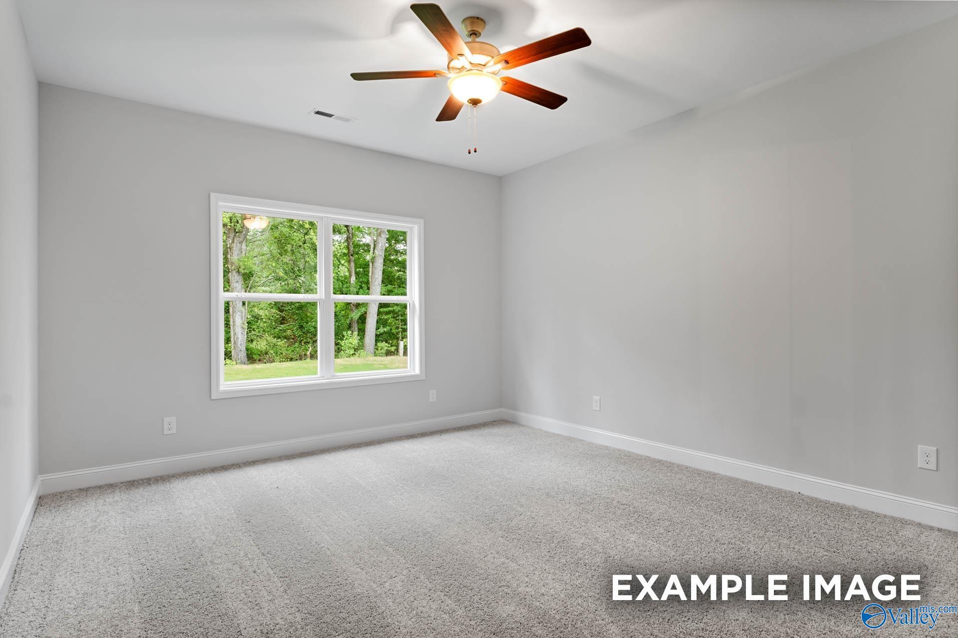 Bright secondary bedroom with ceiling fan, gray walls, and large window to green trees in Davidson Homes The Daphne, Meridianville, Alabama