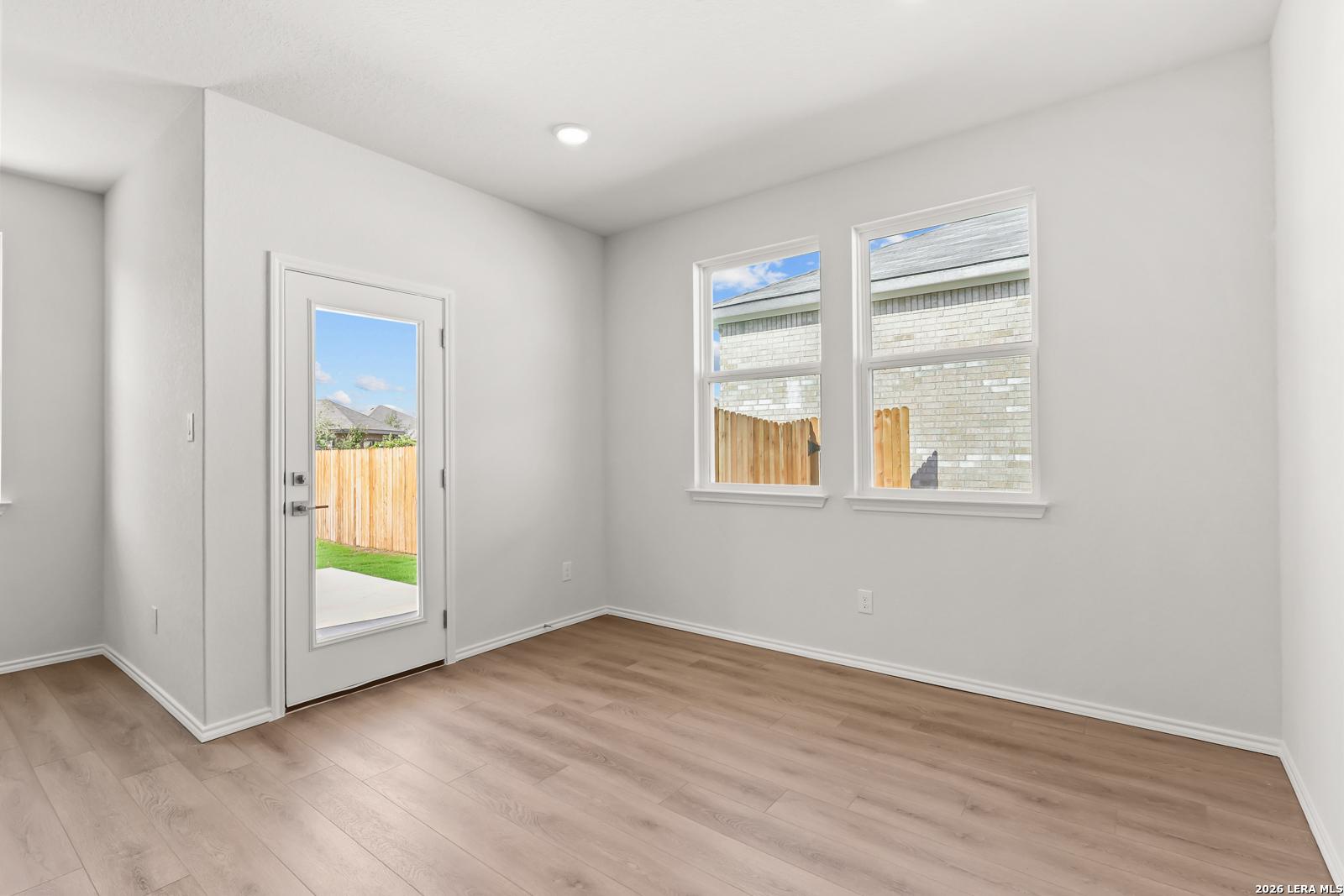 Bright dining area with wood-look flooring, glass back door, and fenced backyard views in Davidson Homes' Daphne I, San Antonio