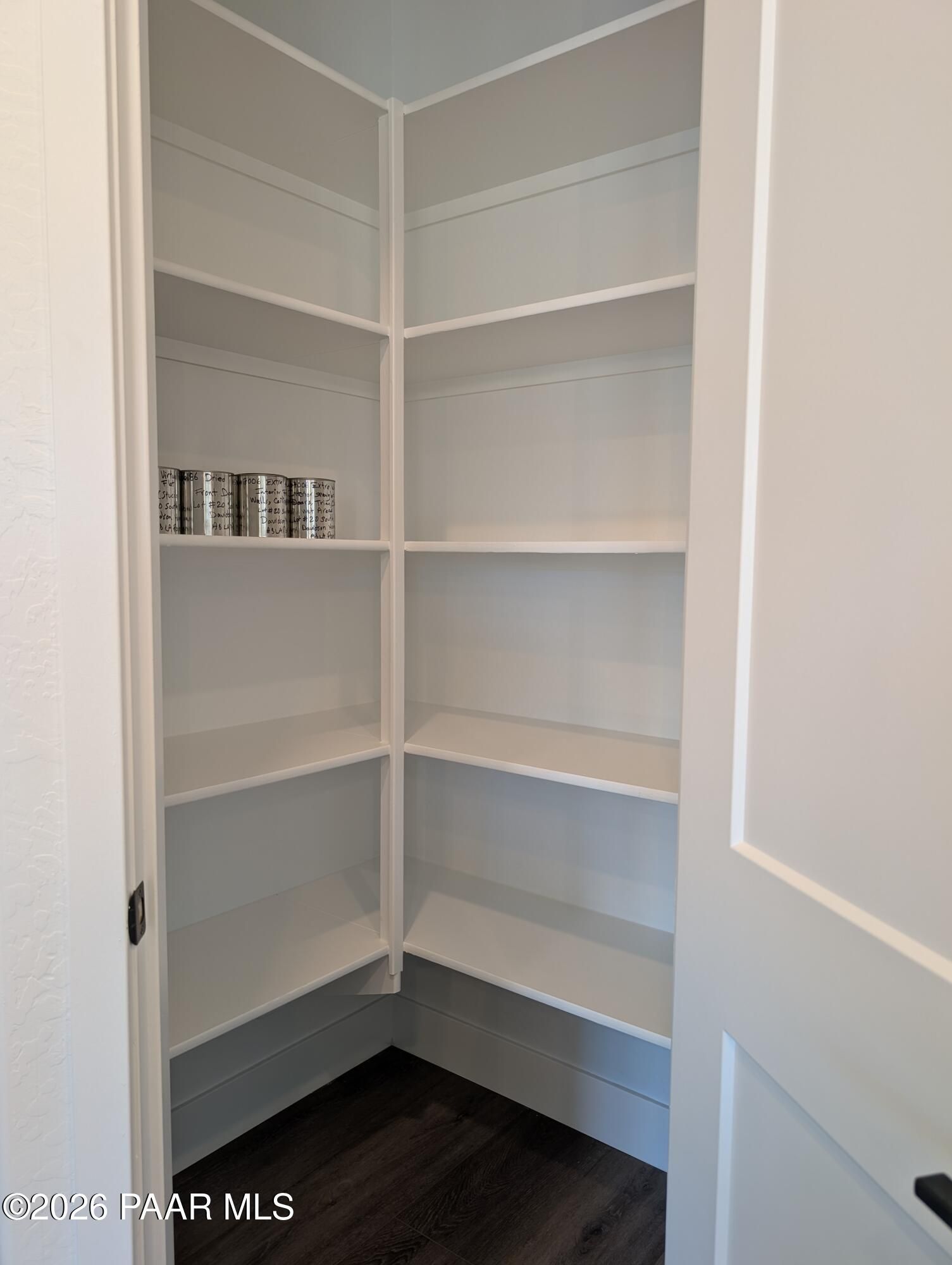 Spacious corner walk-in pantry with white shelving and stocked canned goods in Davidson Homes The Sheridan II G, Prescott, Arizona
