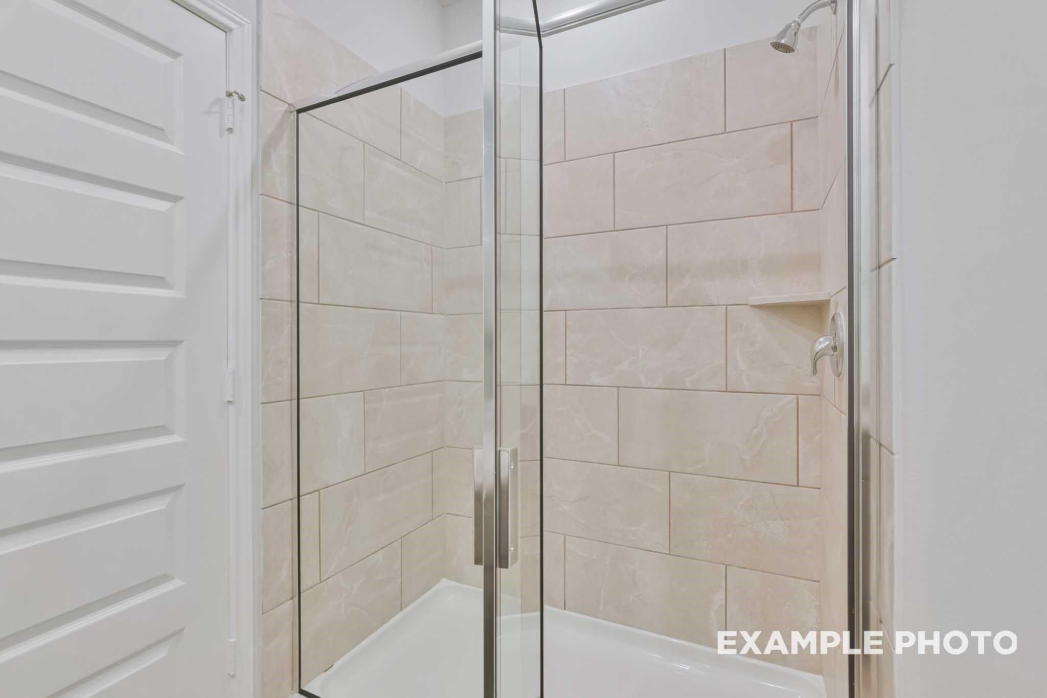 Frameless glass shower with beige subway tile walls in master bath of Davidson Homes The Frio F, Conroe, Texas