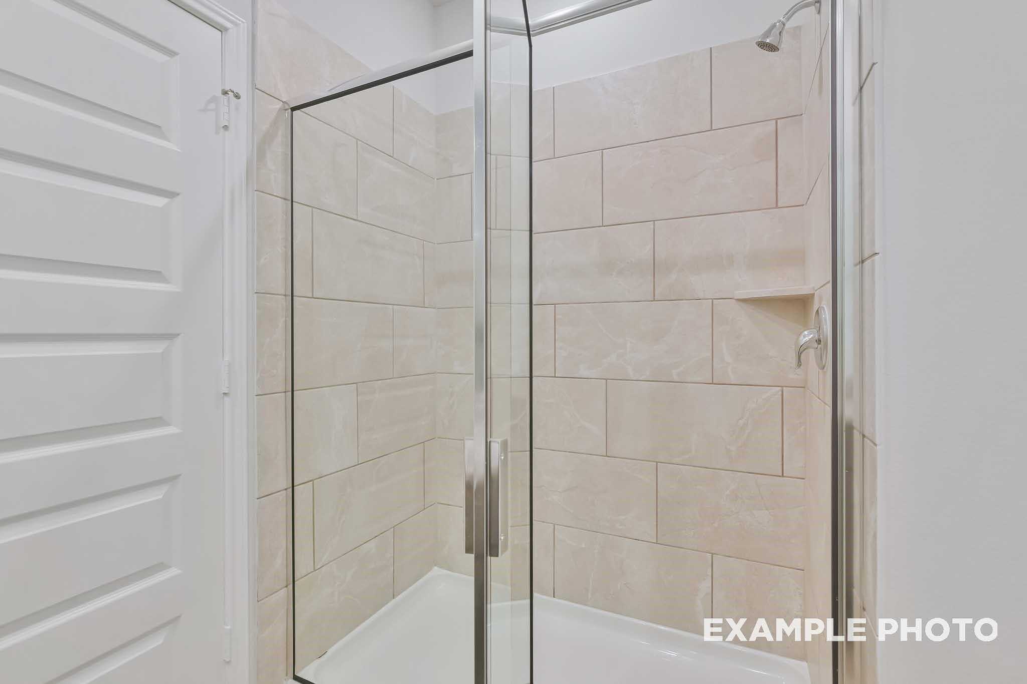Frameless glass shower with beige subway tile walls in master bath of Davidson Homes The Frio F, Conroe, Texas