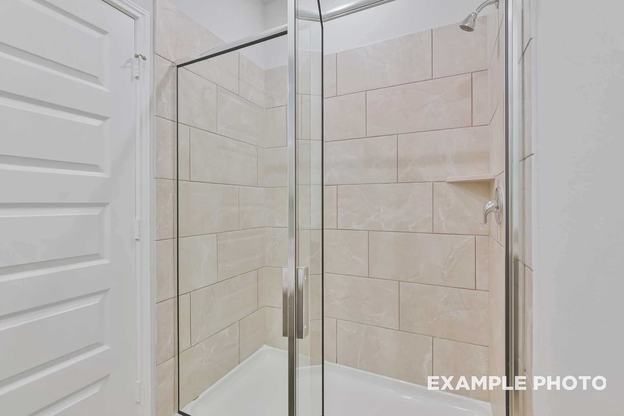 Frameless glass shower with beige subway tile walls in master bath of Davidson Homes The Frio F, Conroe, Texas