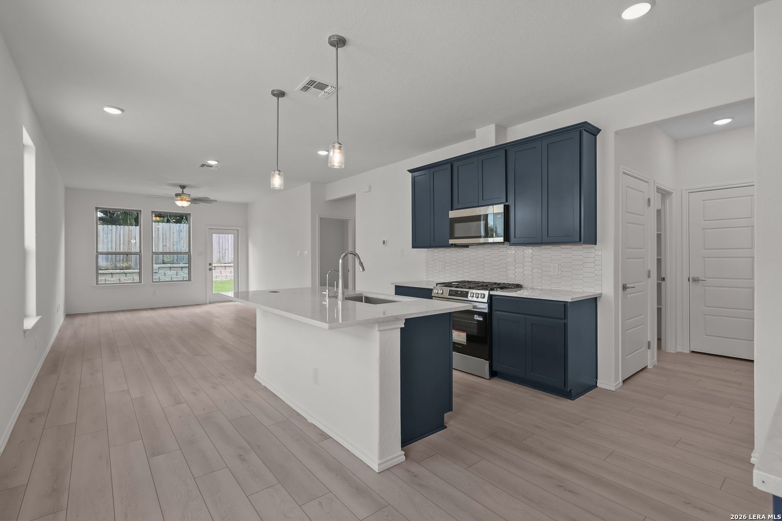Modern kitchen with navy cabinets, quartz island, and open floor plan in The Gillian C home, Meadows at Oak Creek, San Antonio.