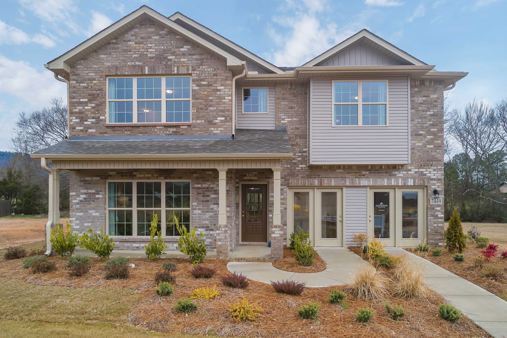 Modern two-story brick home exterior at The Reserve at Overton in Hampton Cove, Alabama with covered porch and landscaped yard