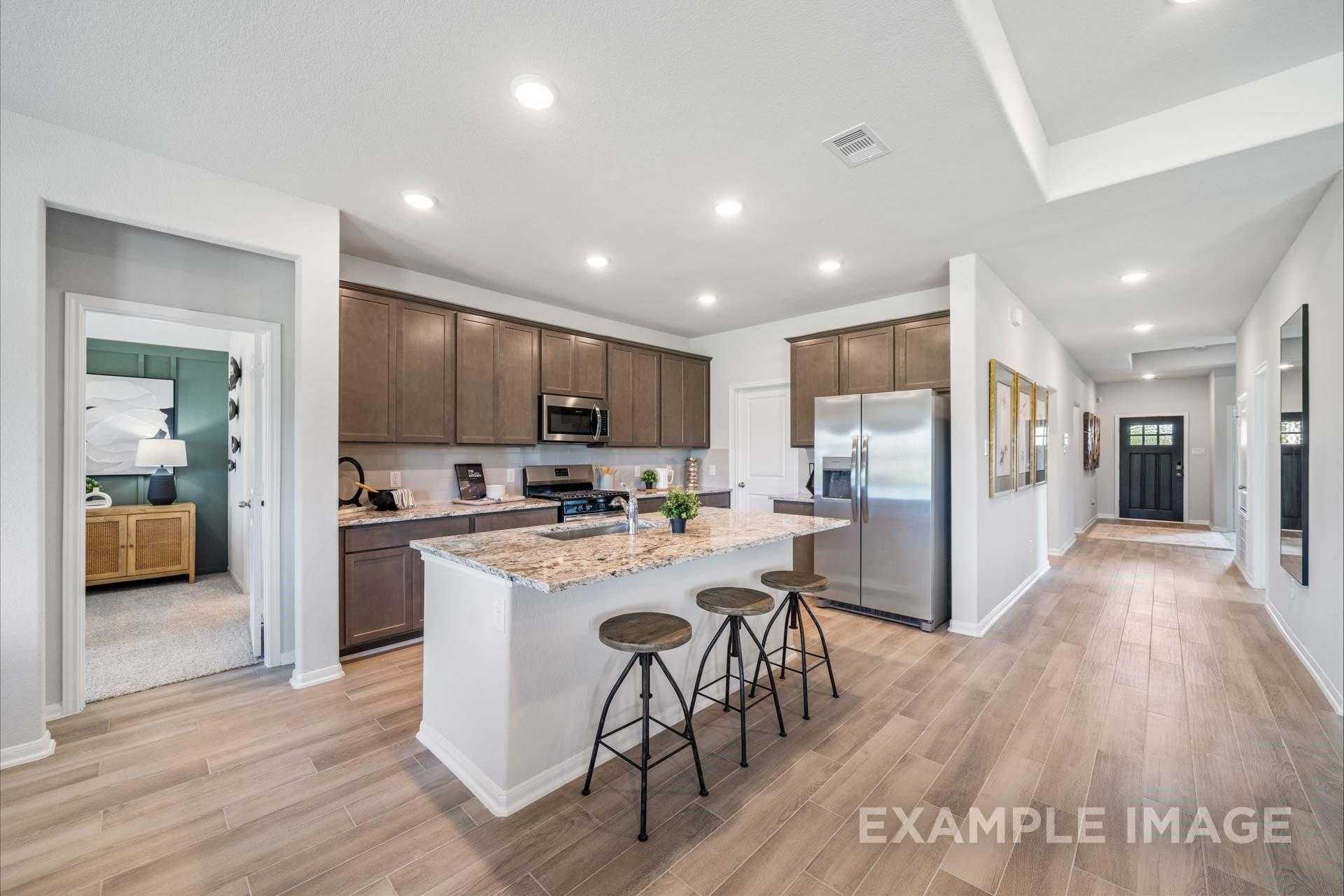 Modern open-concept kitchen with granite island, stainless appliances, wood cabinets in Davidson Homes The Acadia A, Texas City