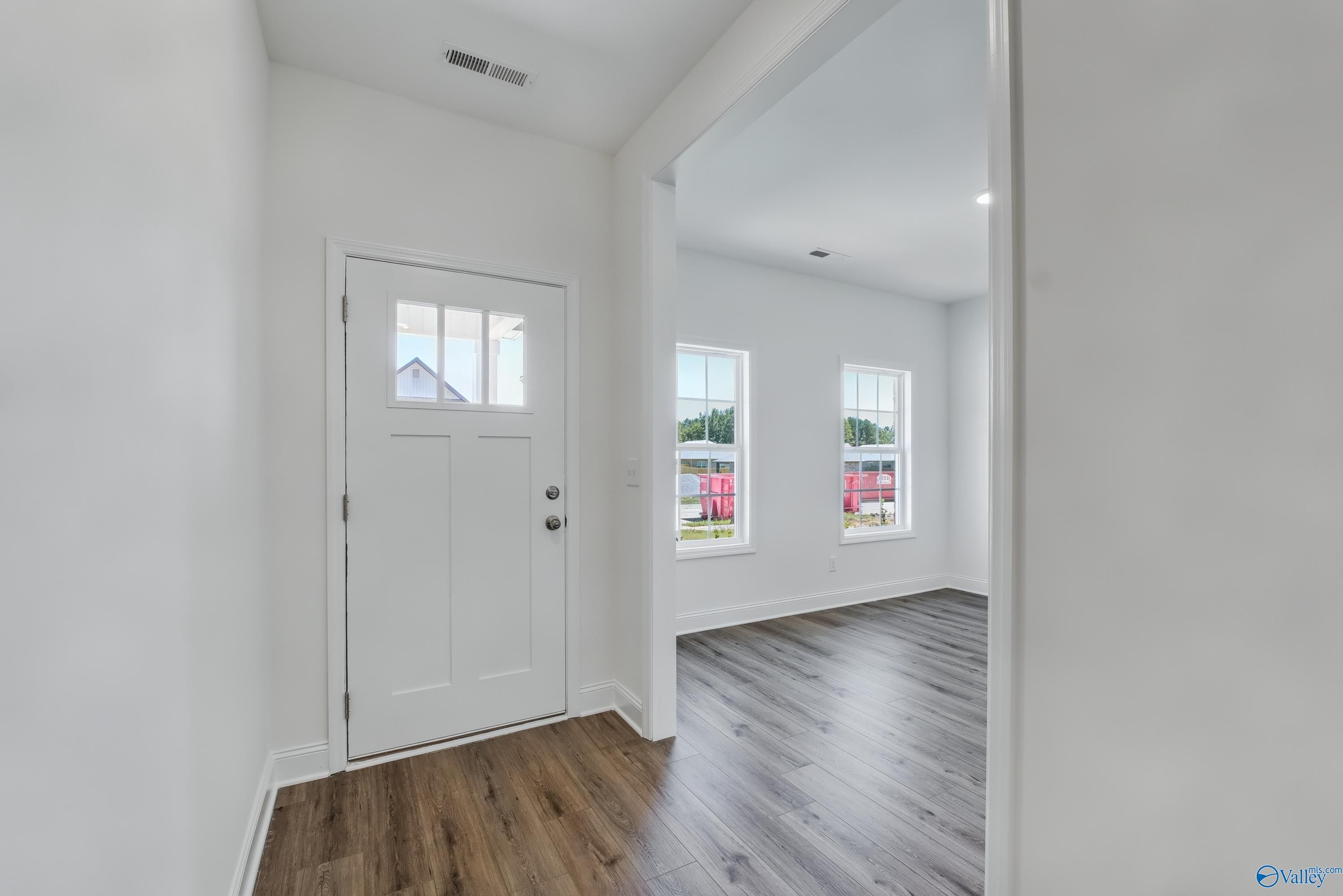 Bright entryway with white paneled door, large windows, and hardwood floors in Davidson Homes The Shelby A, Arab, Alabama